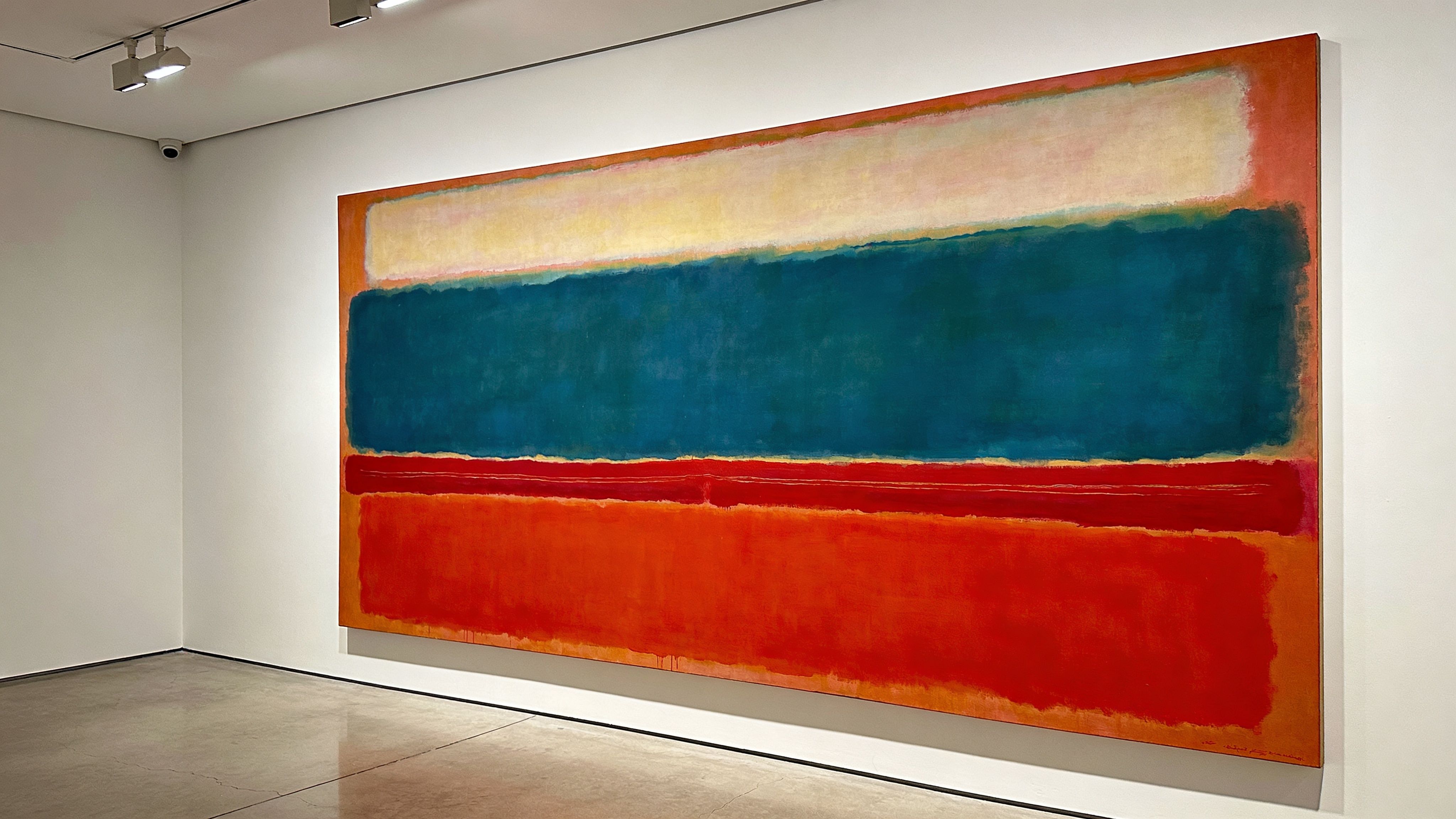 A large Mark Rothko abstract expressionist painting featuring horizontal color bands hanging in a modern gallery.
