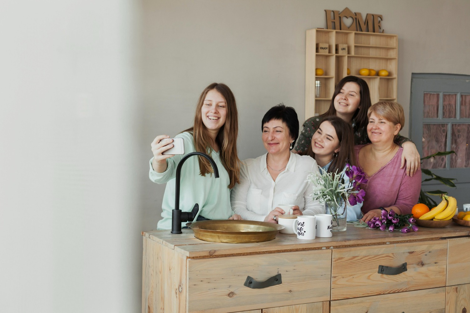 A group of five women taking a groufie by a kitchen countertop