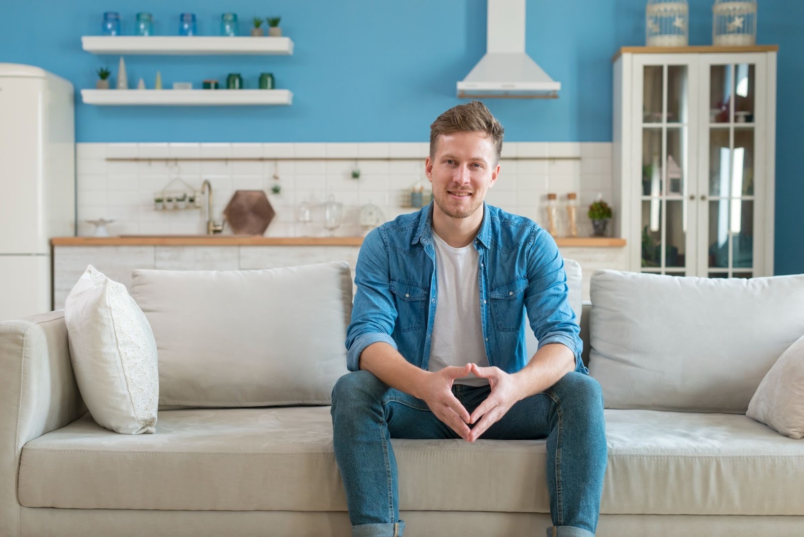 A man sitting comfortably on a couch in a cozy living room, depicting what it’s like living in a recovery housing