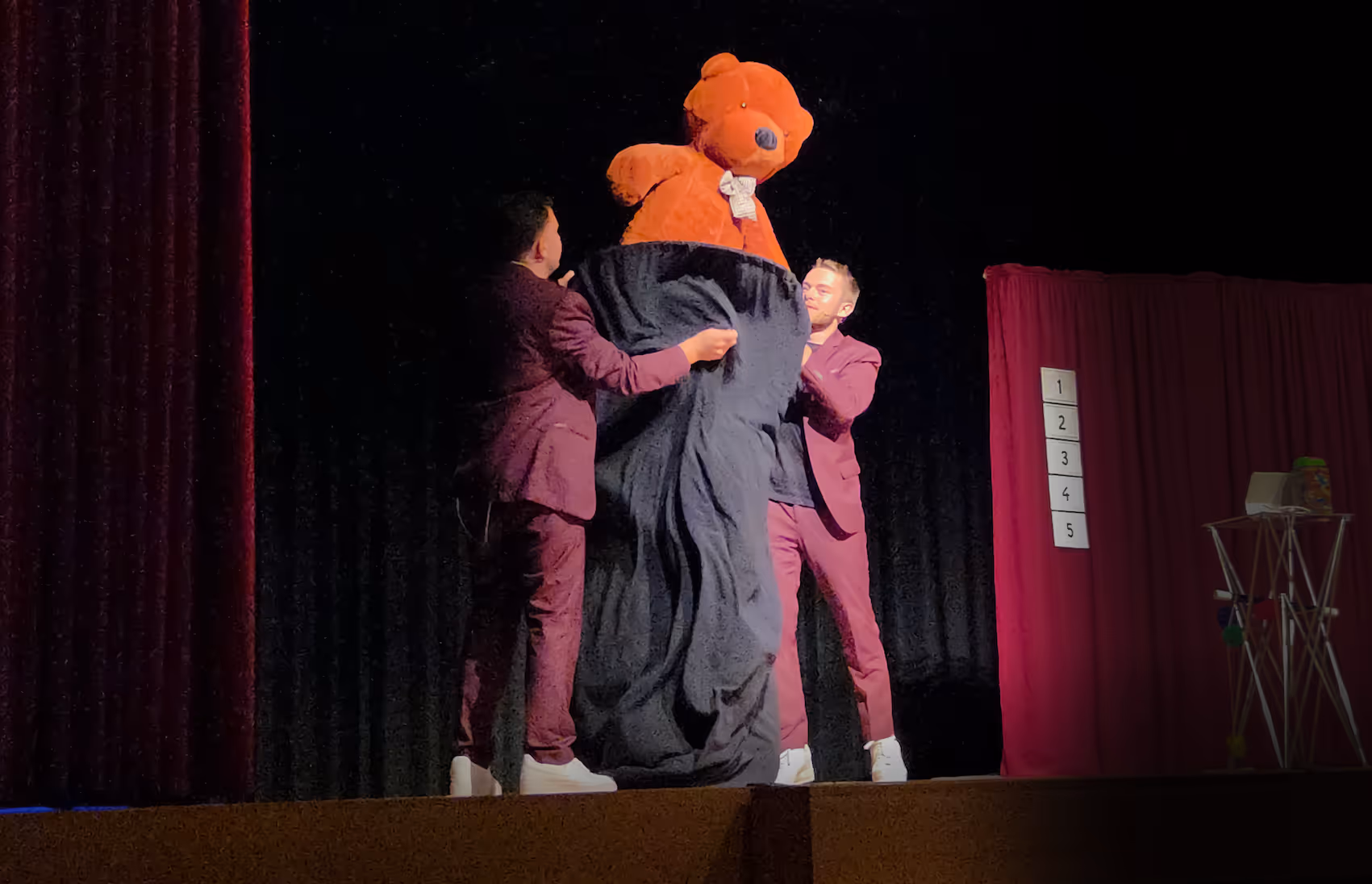 Un duo de magicien fait apparaître un ours en peluche sur une scène à versoix