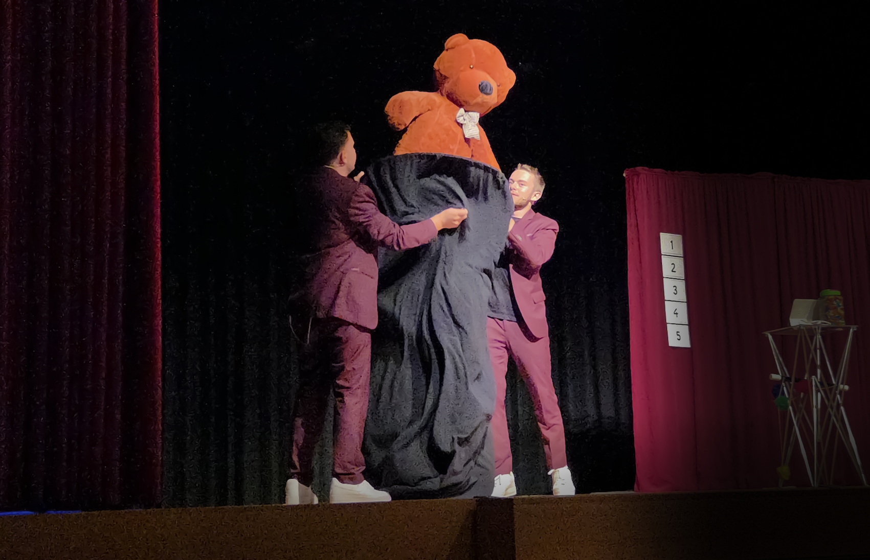 Un duo de magicien fait apparaître un ours en peluche sur une scène à versoix