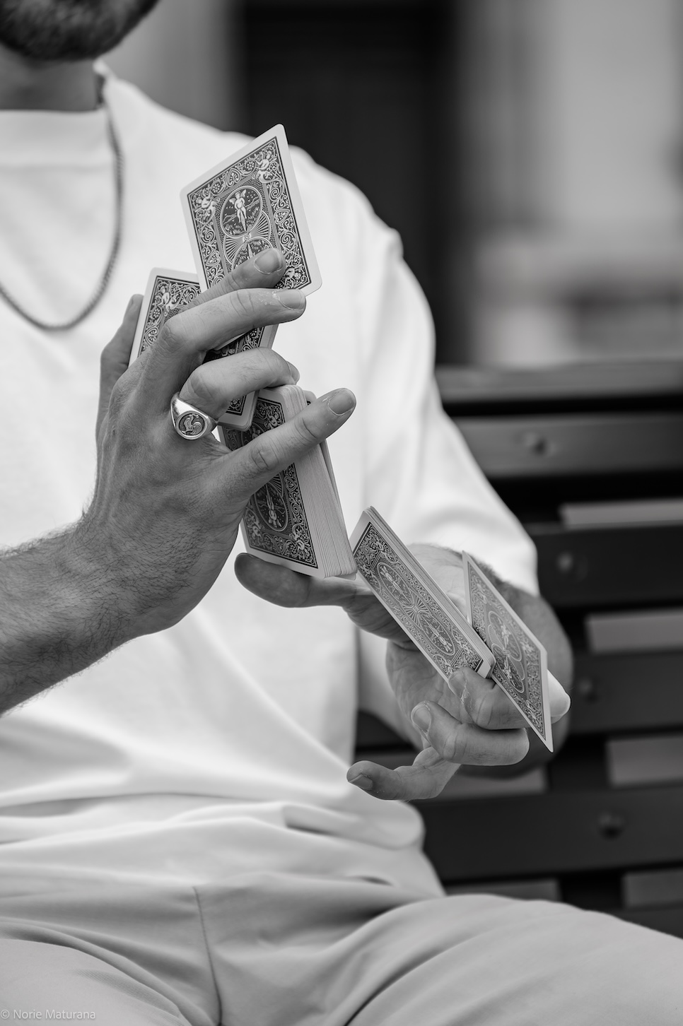 Un homme effectuant un tour de cartes avec ses mains, assis sur un banc.