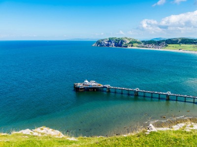 Llandudno Pier stretching into the bay with the Great Orme headland visible on a sunny day