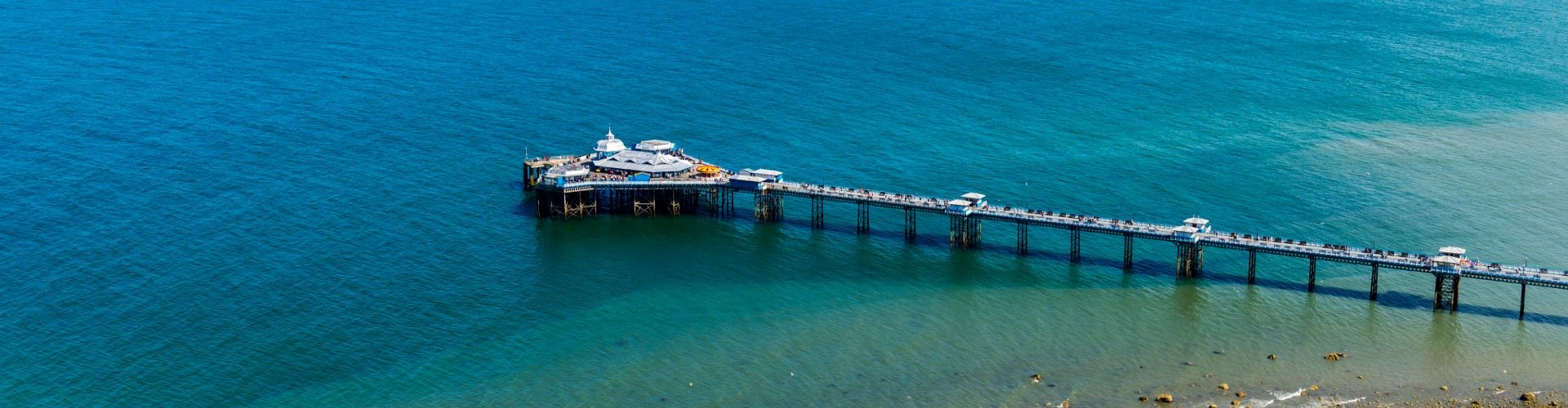 Aerial view of Llandudno Pier and Victorian pavilion over turquoise waters on a summer day