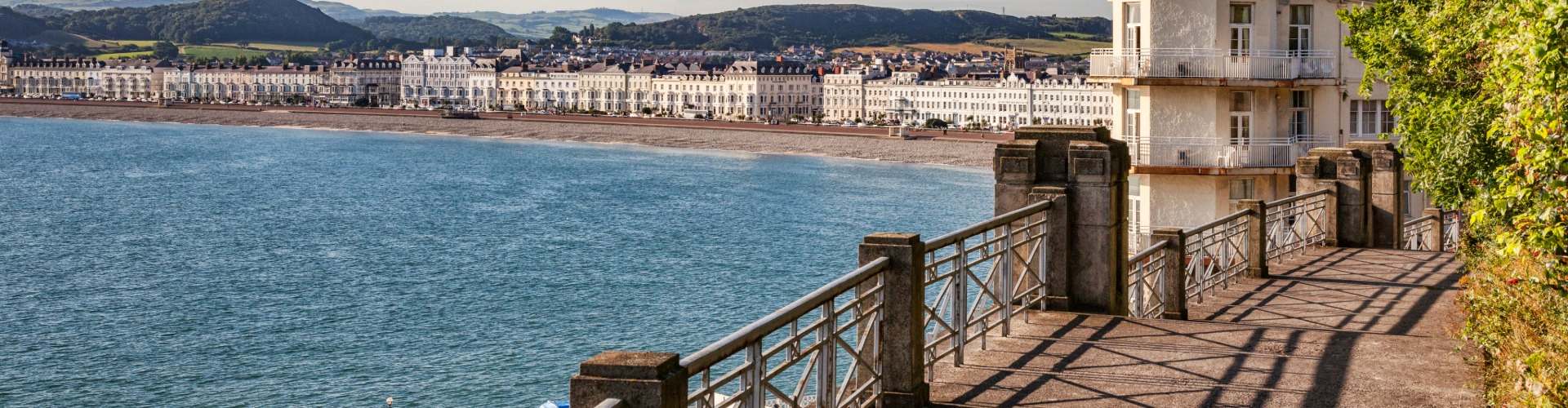 Llandudno seafront promenade and curving bay of white hotels, with green hills behind in North Wales