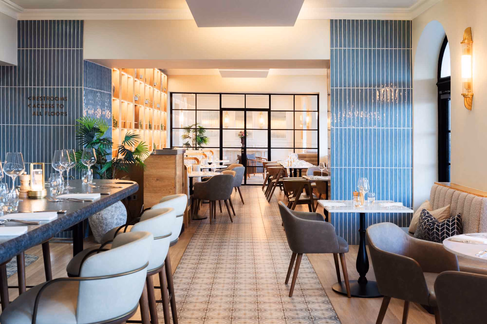 Open-plan dining room with blue-tiled columns and banquette seating at The Goat restaurant, Llandudno