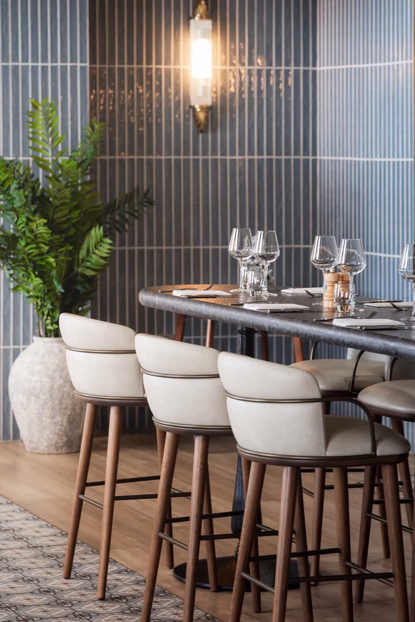 Bar seating at The Goat restaurant, Llandudno, with cream stools and wine glasses set along a marble-topped counter