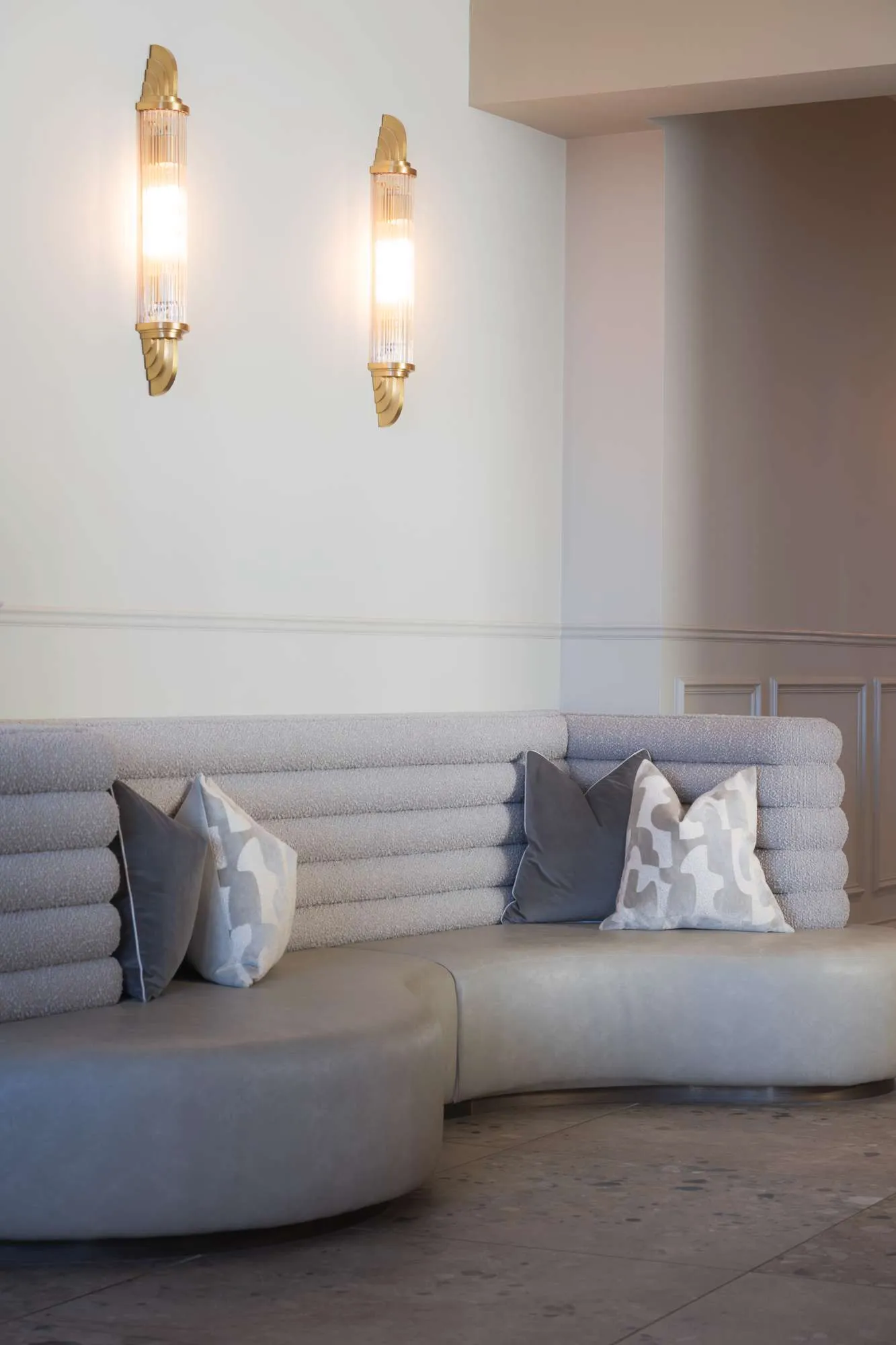 Curved cream lounge seating with cushions and wall lights in the bar.