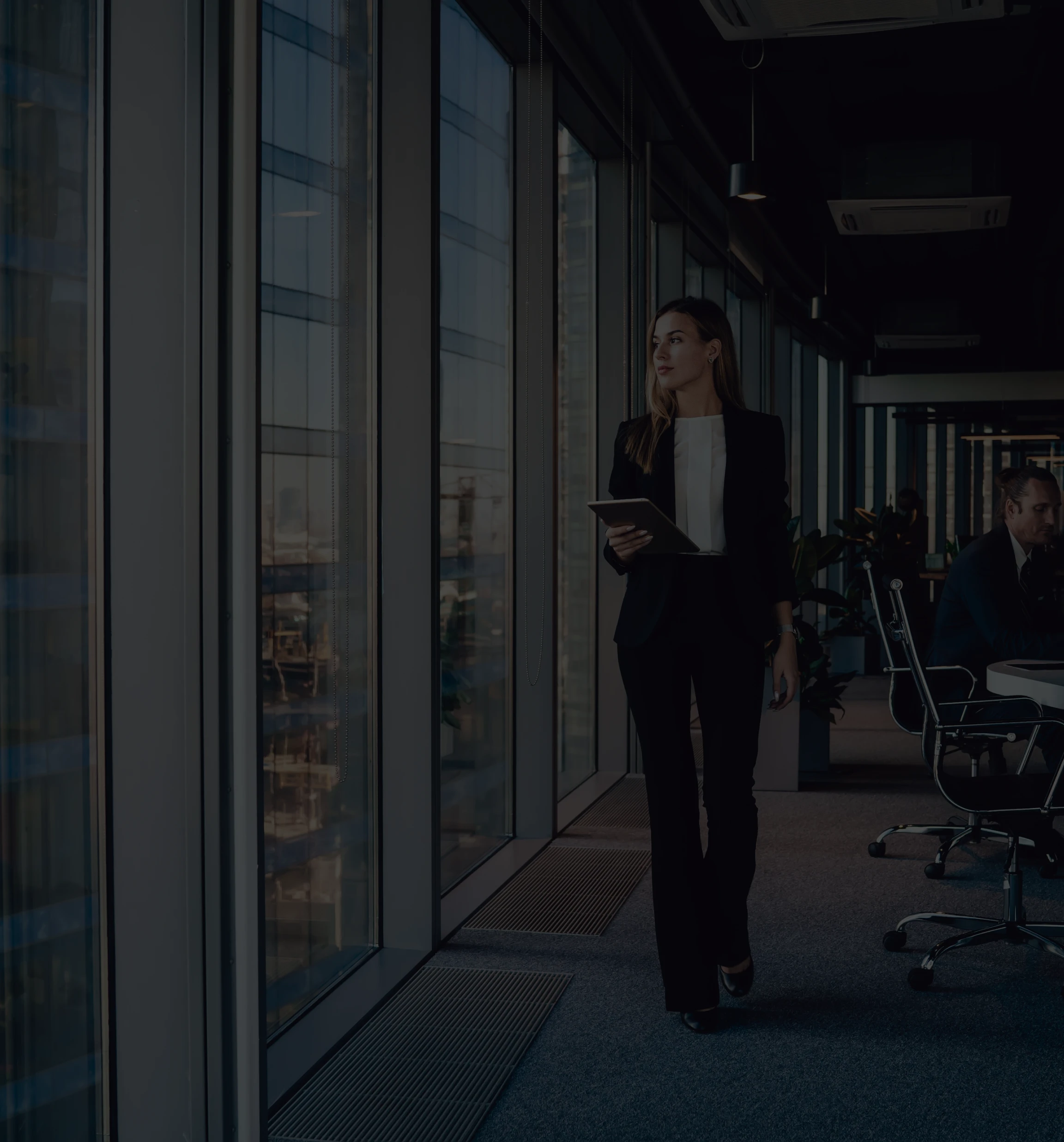 Premium executive services and corporate leadership: A female professional in a business suit walking past floor-to-ceiling windows in a modern office, illustrating high-stakes logistics and executive-level performance.