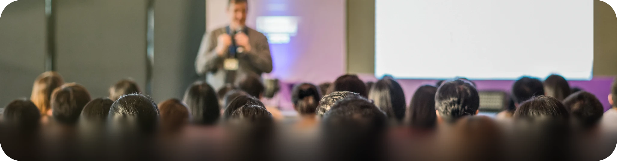 Professional corporate event logistics: An audience attending a keynote presentation at a large venue, illustrating event transportation and group coordination services.