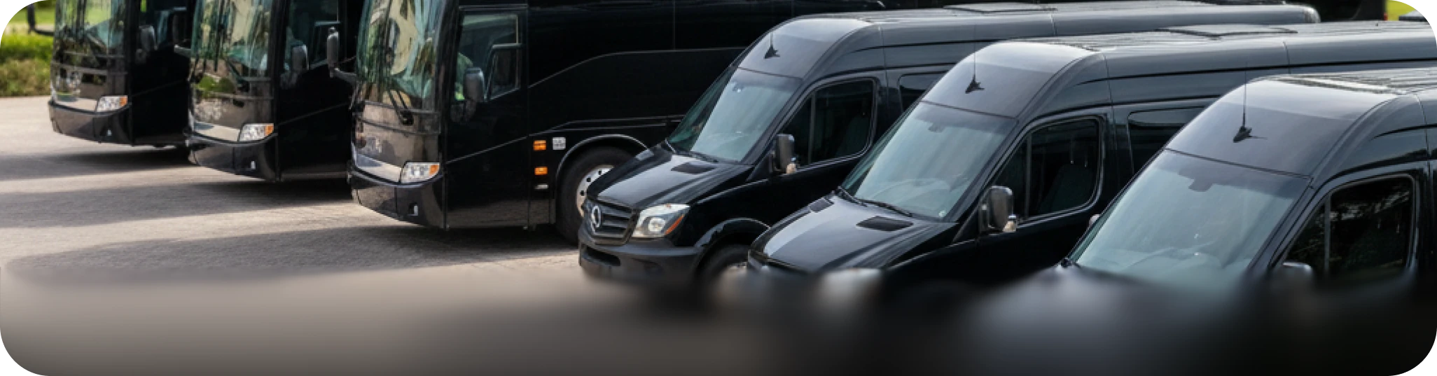 Professional ground transportation fleet: A line of sleek black luxury passenger vans and chauffeured charter buses for corporate and group travel.