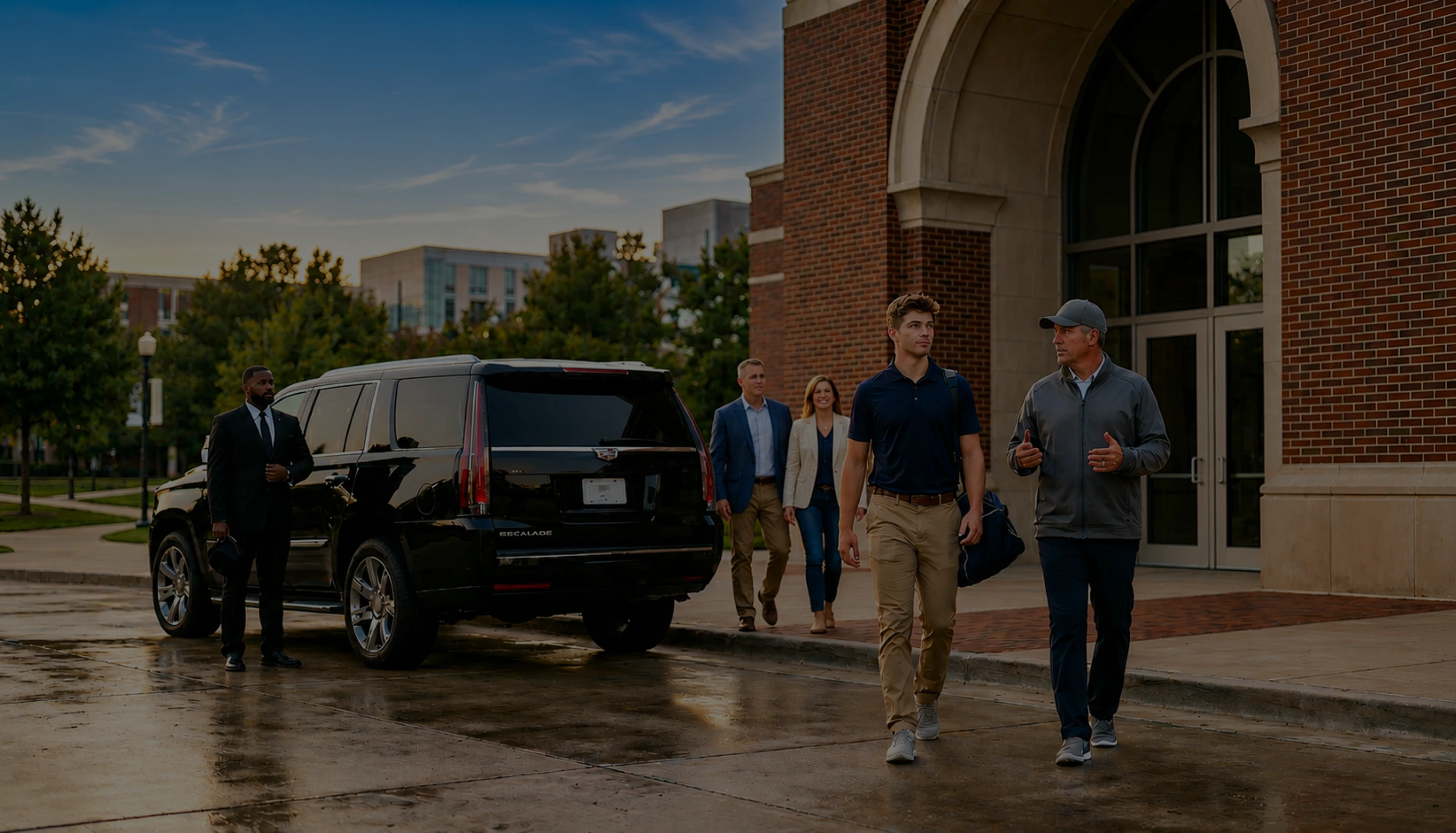 Savoya premium SUV service: A professional chauffeur waits with a luxury black SUV for clients arriving at a corporate office or university campus venue.