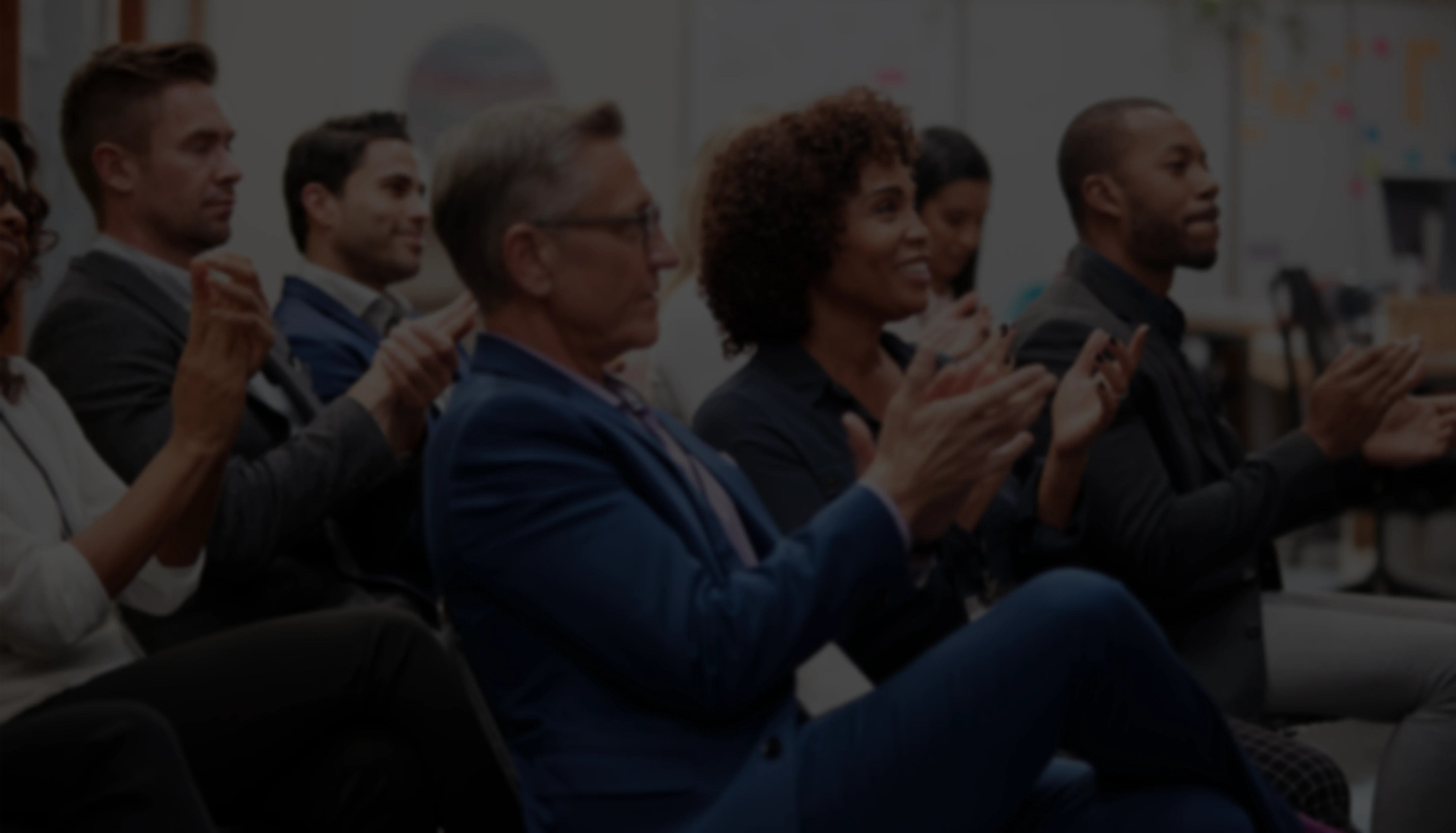 Professional audience engagement: A group of executives and business leaders clapping at a corporate seminar or industry conference.