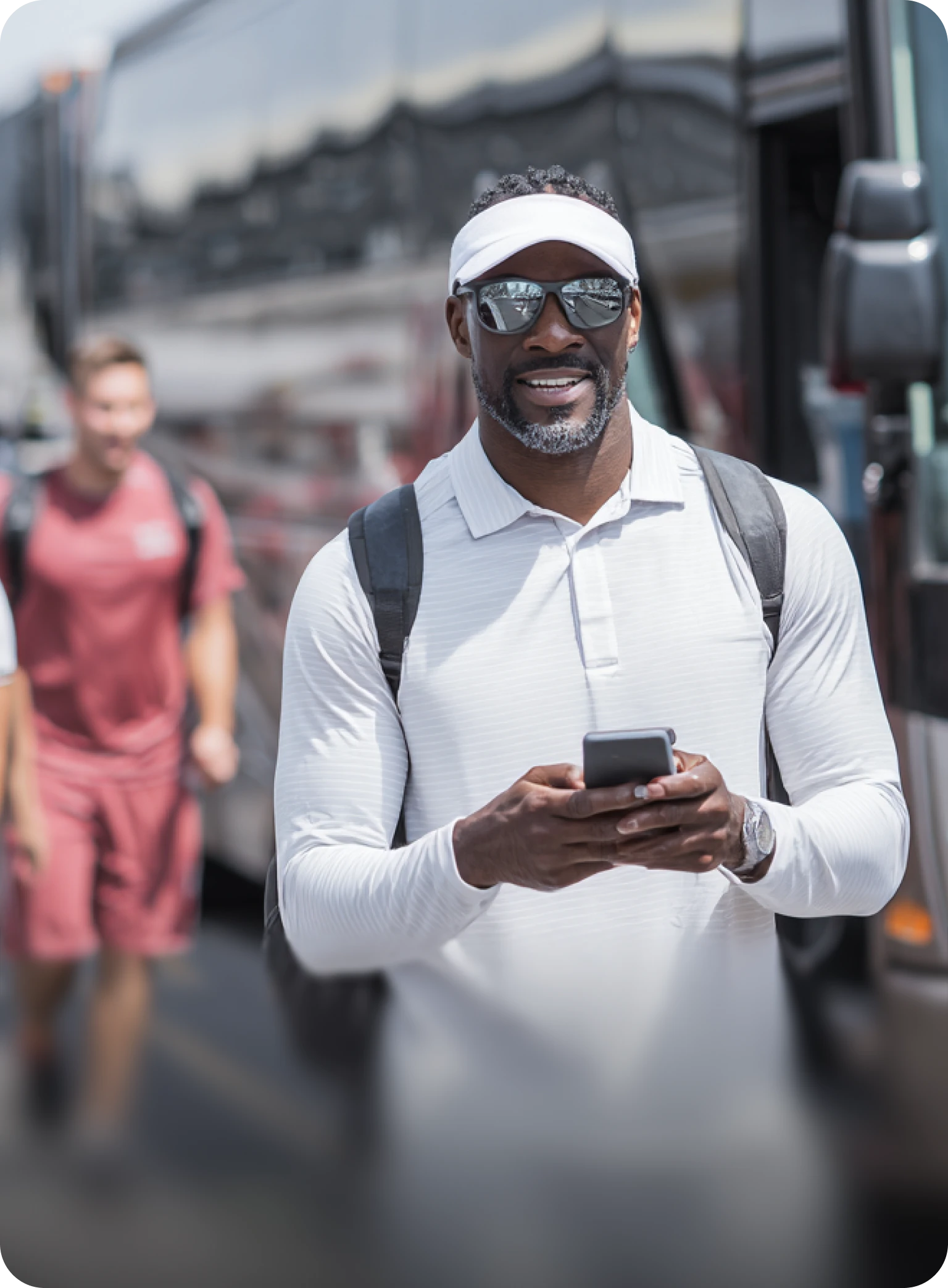 Savoya sports team logistics: A team representative managing travel details on a mobile device as athletes prepare to board a premium executive charter bus.