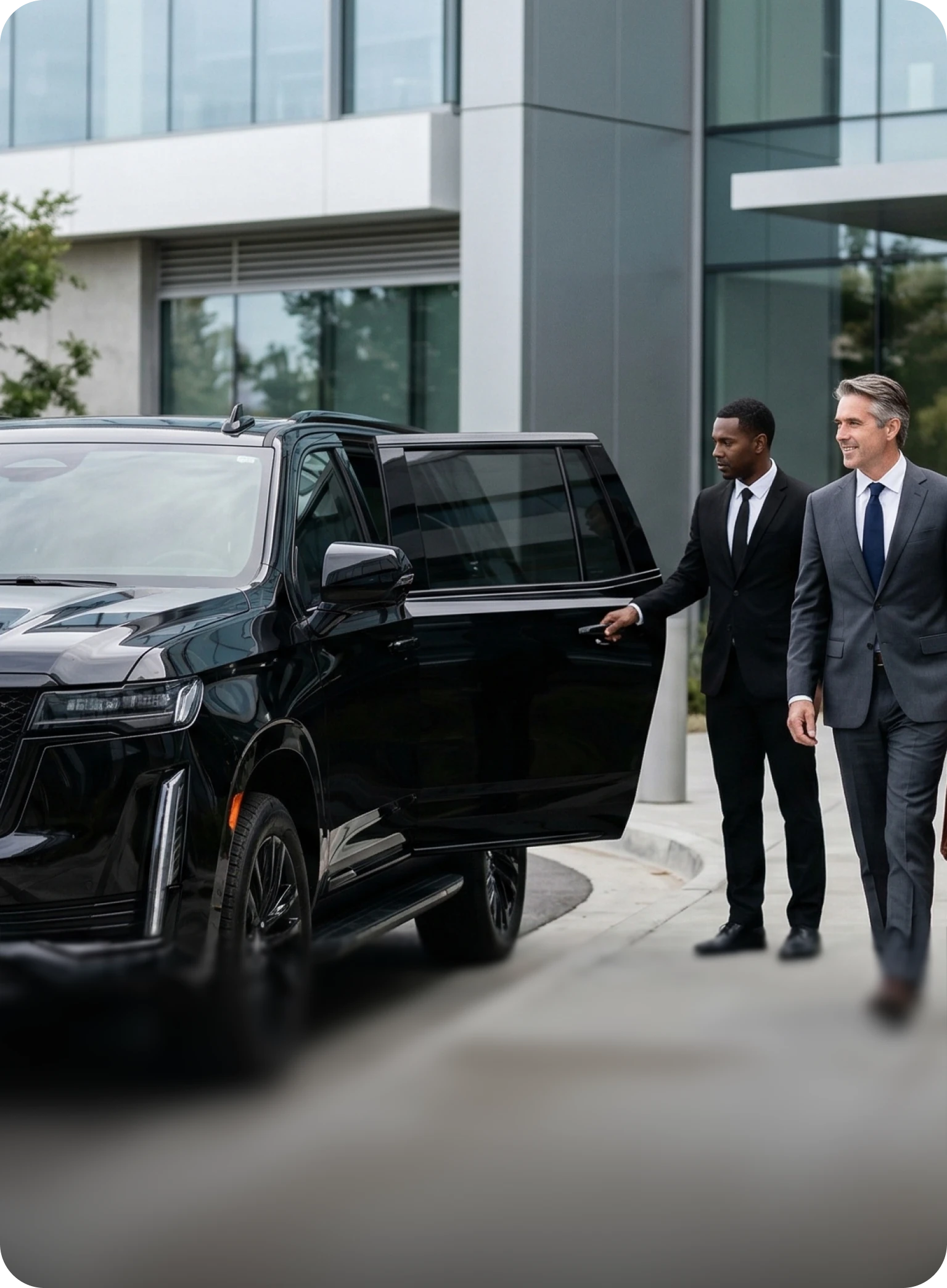 Savoya executive transportation: A private chauffeur assisting a corporate client as they exit a luxury black Cadillac Escalade in front of a modern office building.