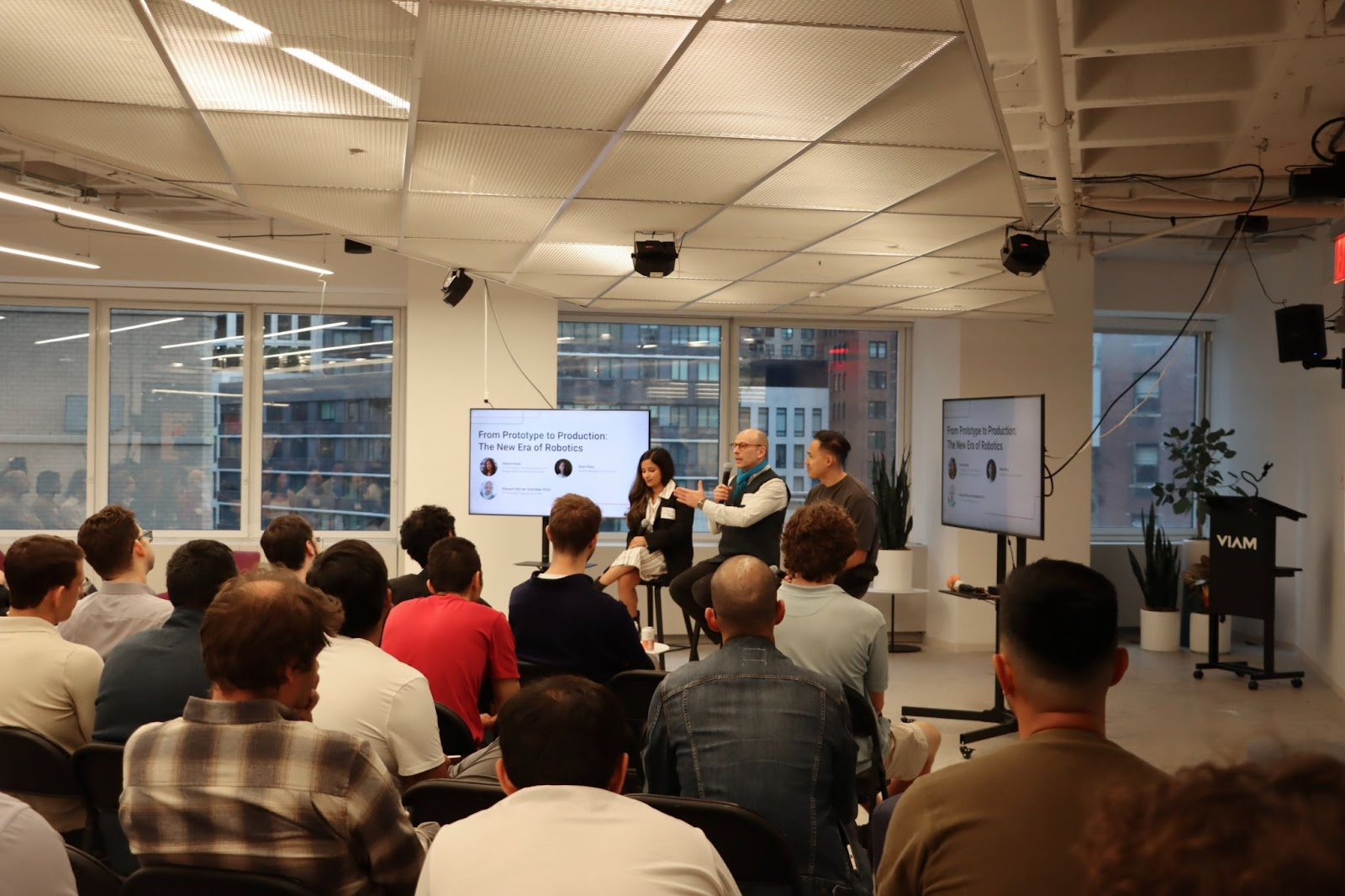 Panelists talking in front of a crowd of attendees 