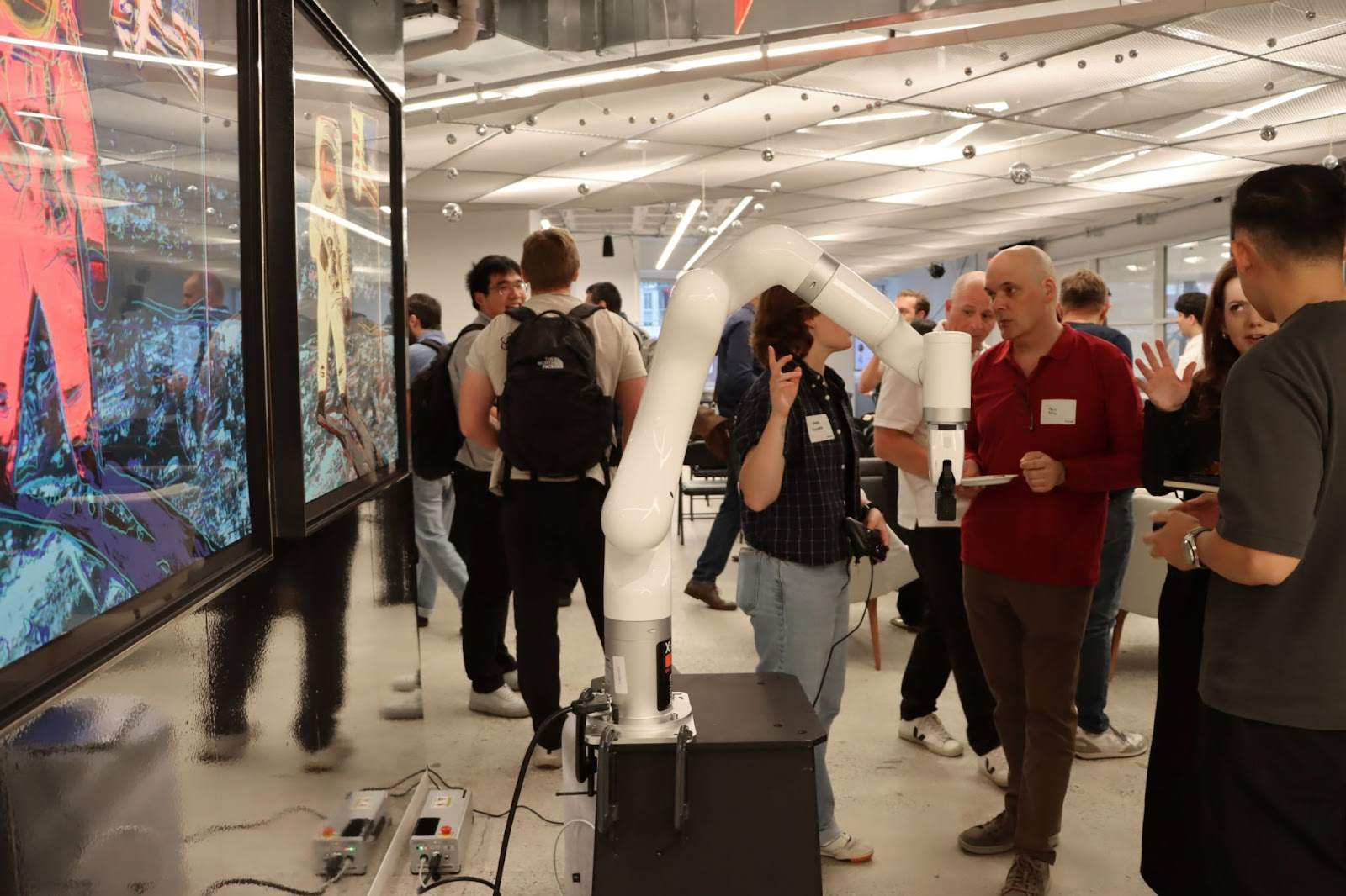 A UFactory robotic arm displayed on the floor while a UFactory team member explains their demo to an event attendeet