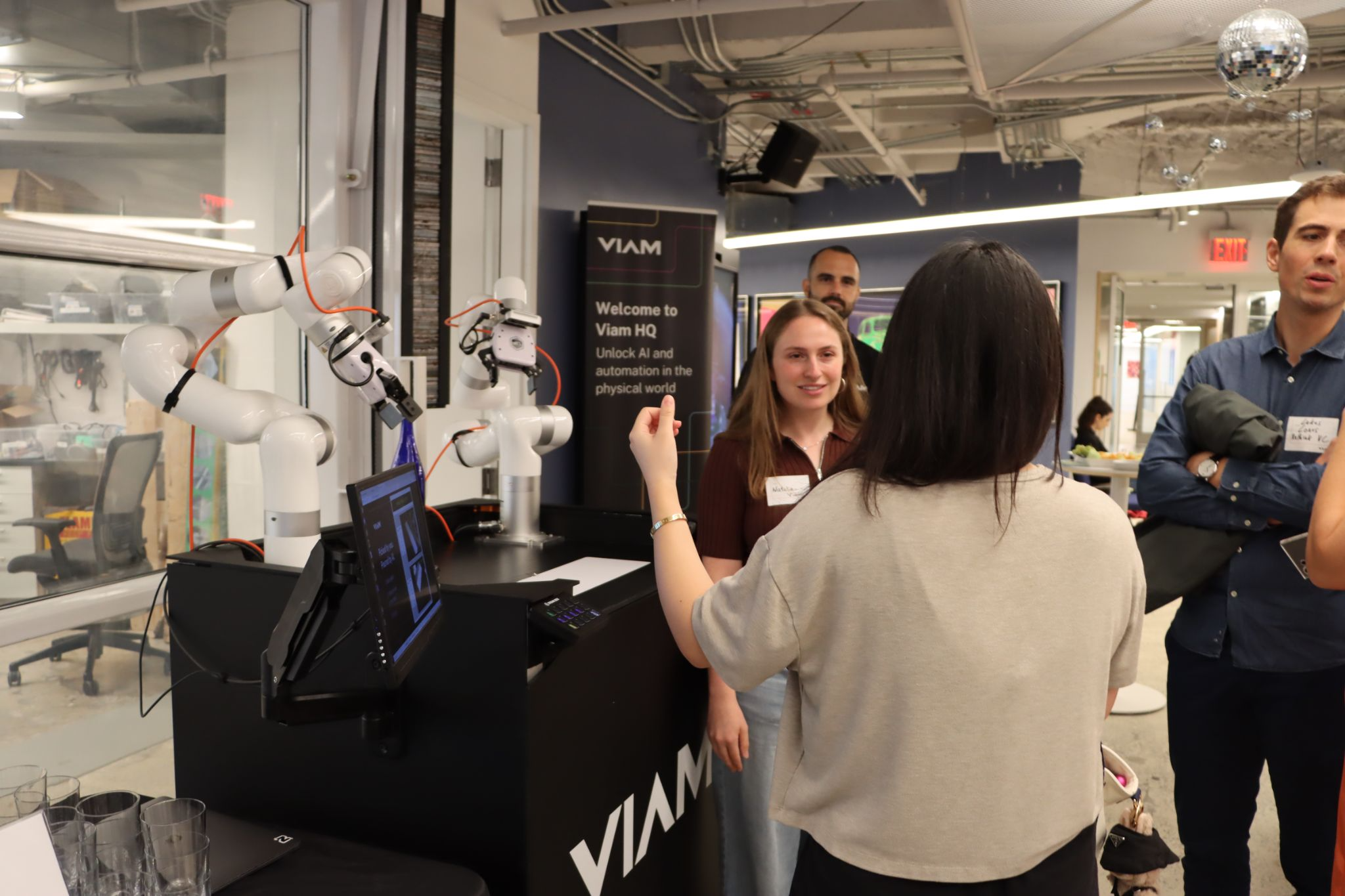 A Viam engineer and an event attendee standing next to Viam's robotics demo discussing how it works