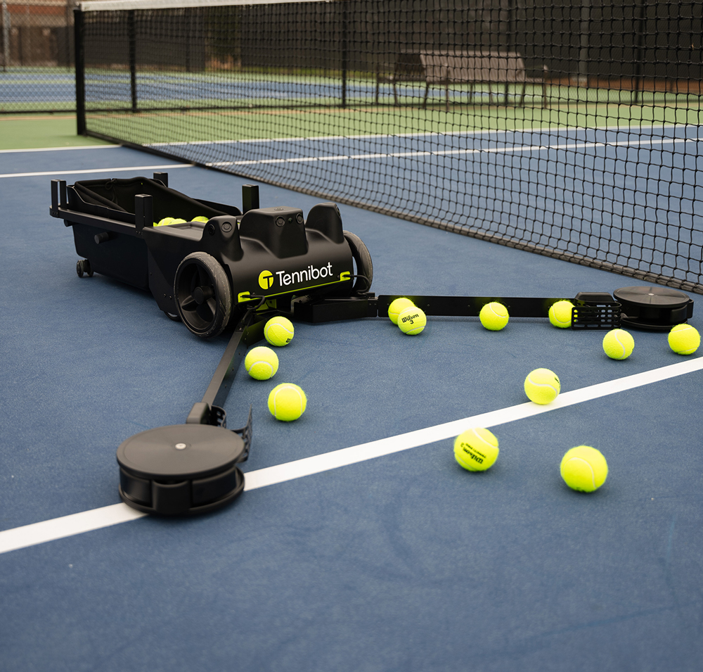A photo of Tennibot moving along a tennis court collecting tennis balls