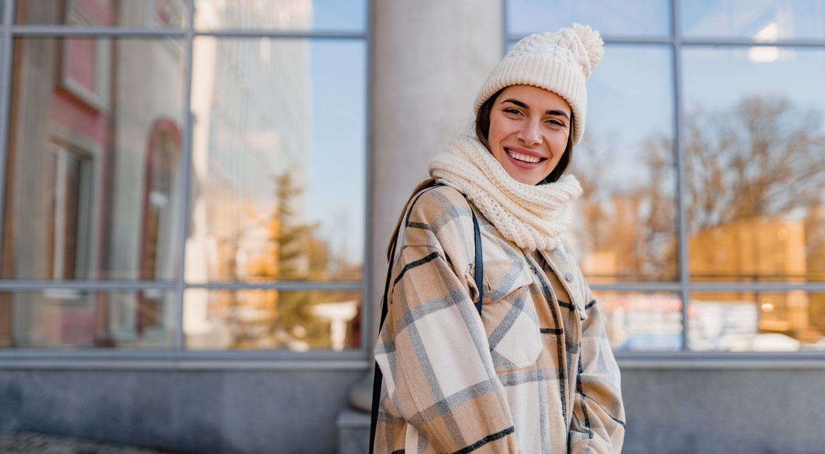 Woman smiling wearing jacket, scarf and hat