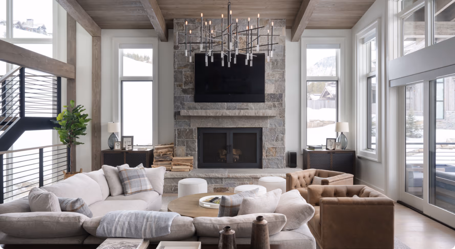 A luxurious, well lit tv area with large, plush couches and chairs, and a modern, geometric chandelier 
