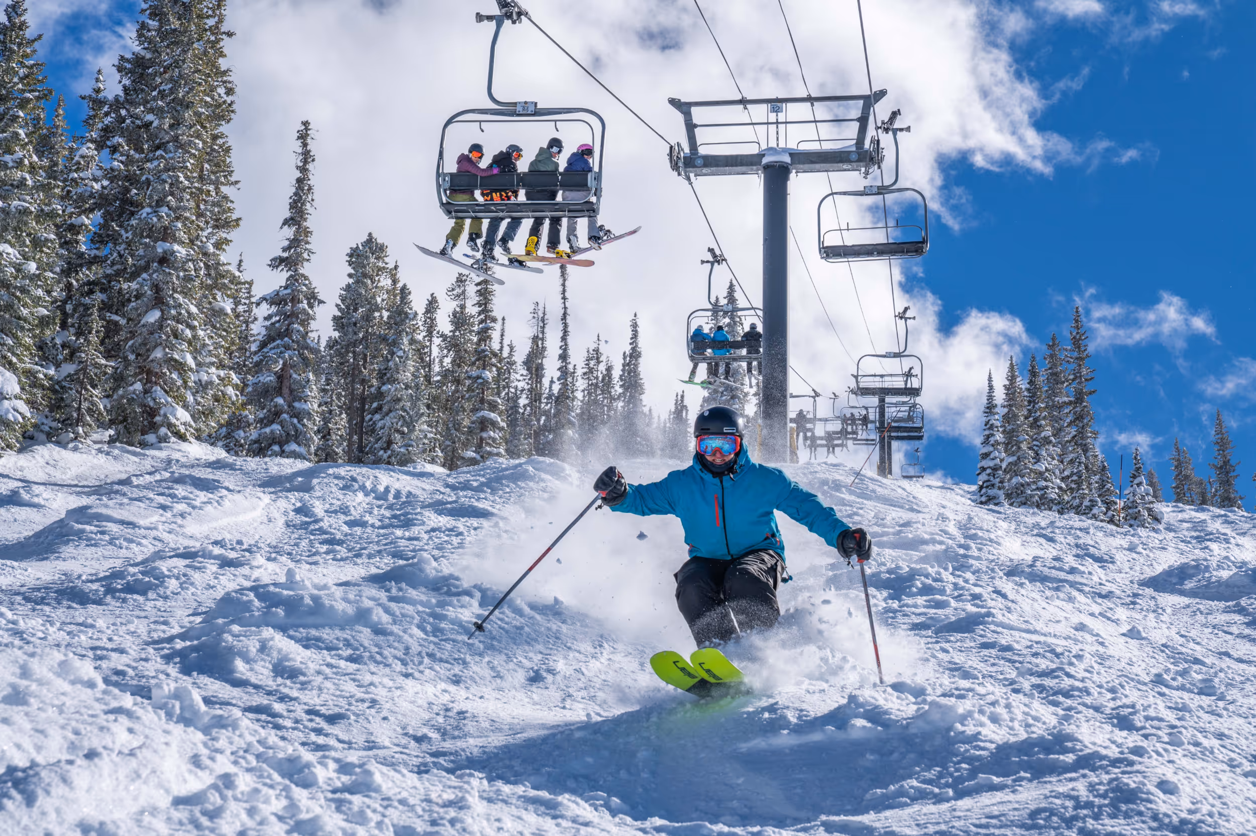 A skier crushing the moguls below a chairlift at Winter Park 