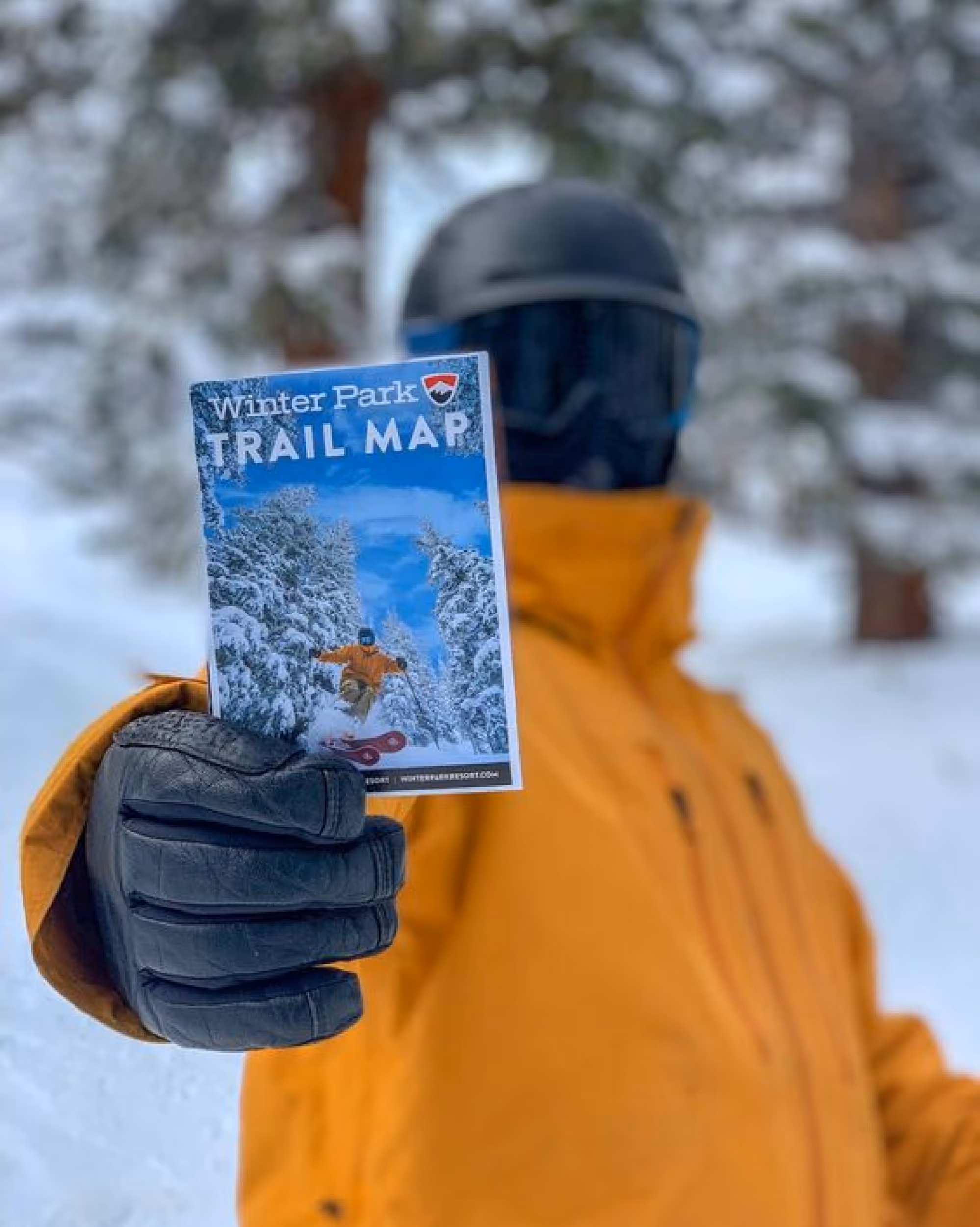Skier holding a trail map of winter park with the image of himself skiing as the trail map cover 