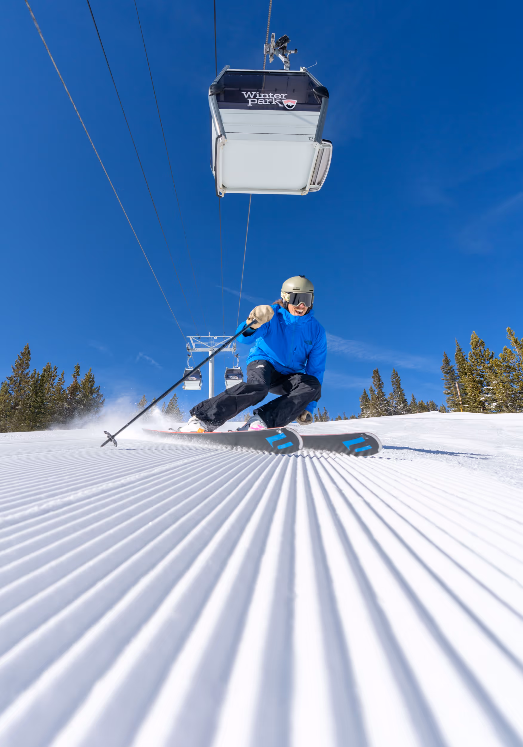 A skier ripping groomer below a gondola at Winter Park 