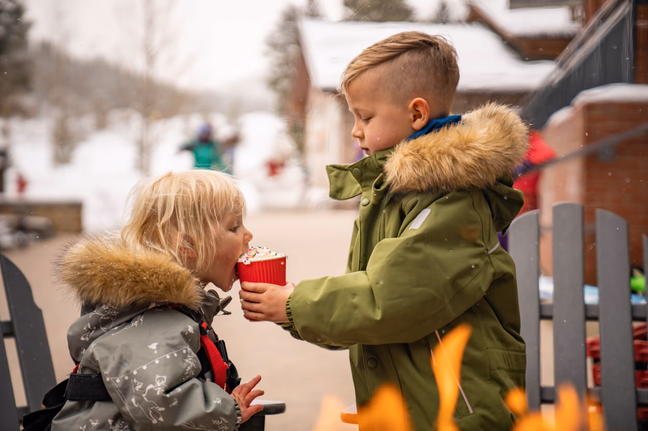 2 young skiers sharing a cup of hot coco