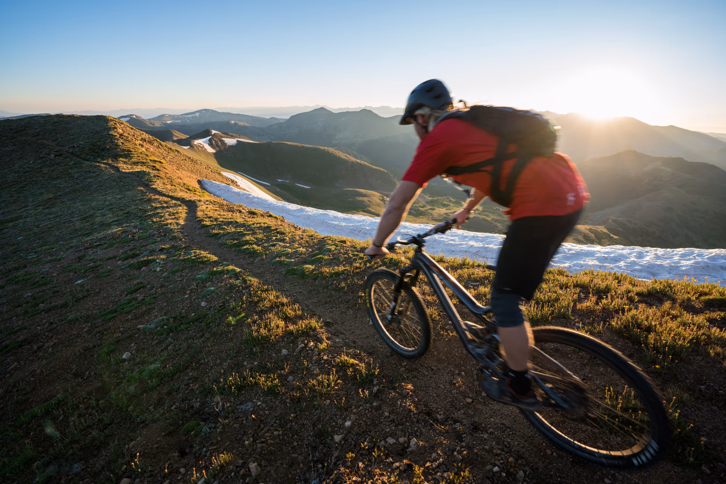 A mountain biker dropping into a downhill section of trail on a ridge line 