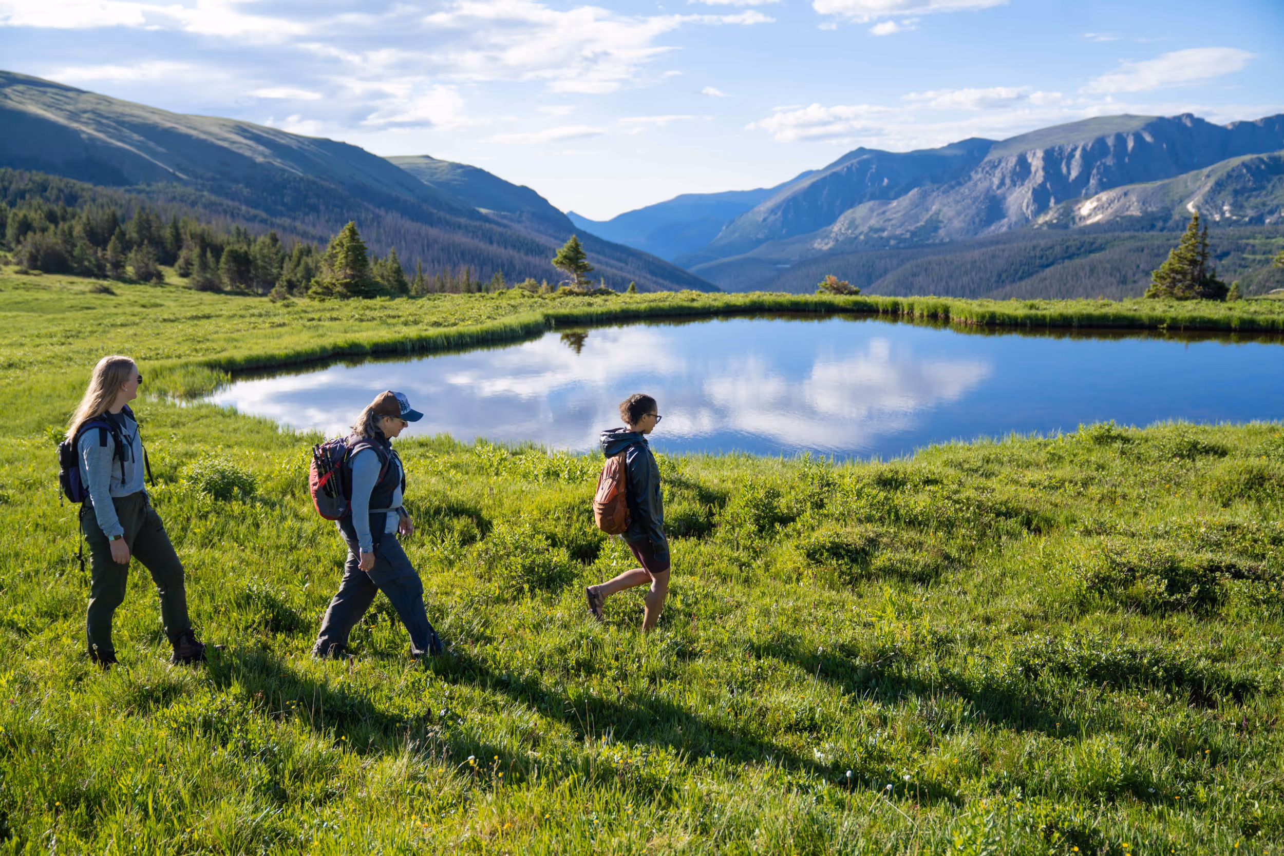 Some hikers hiking in front of a sub-alpine lake 