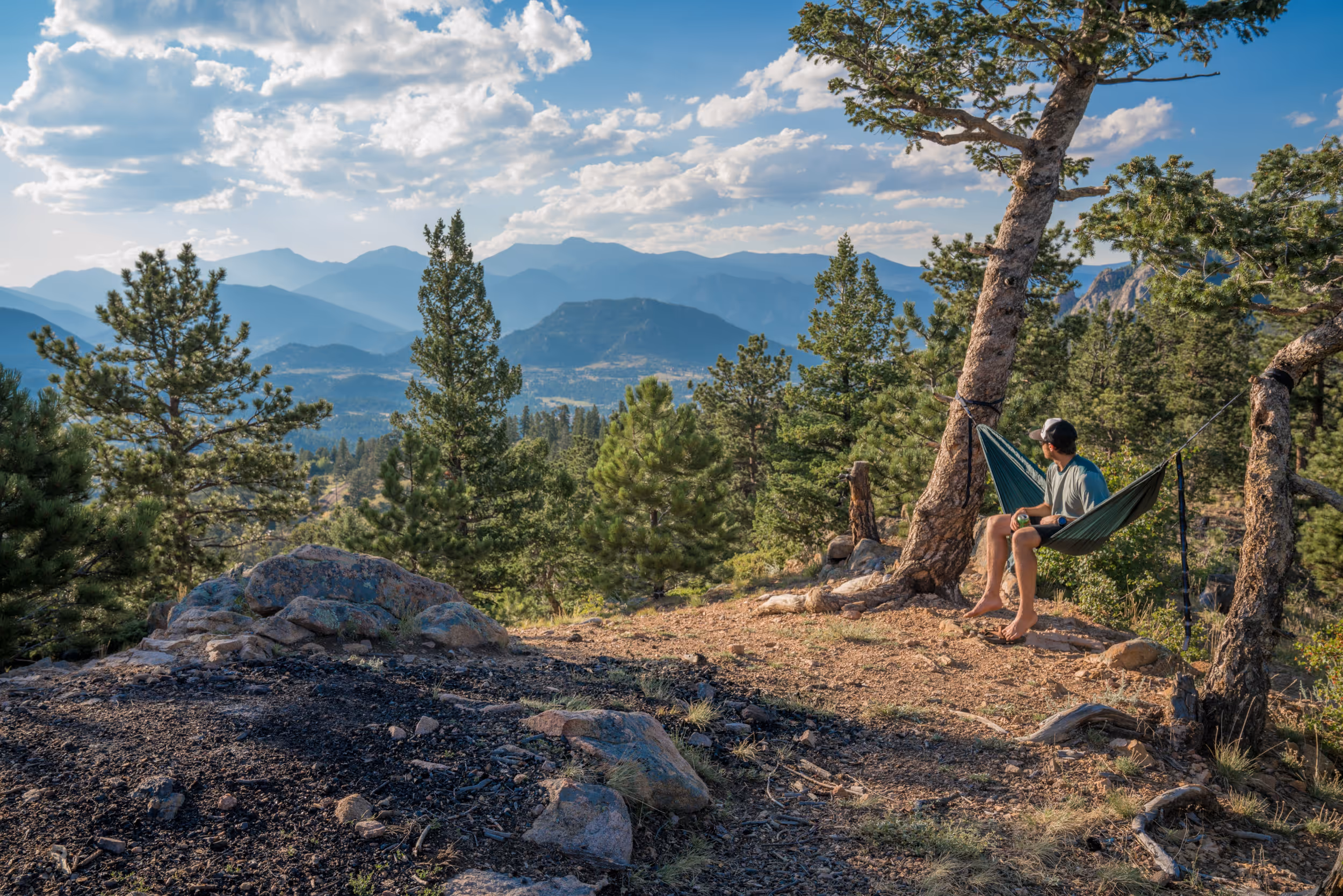 A hiker enjoying a hammock session along the trail overlooking some mountains 
