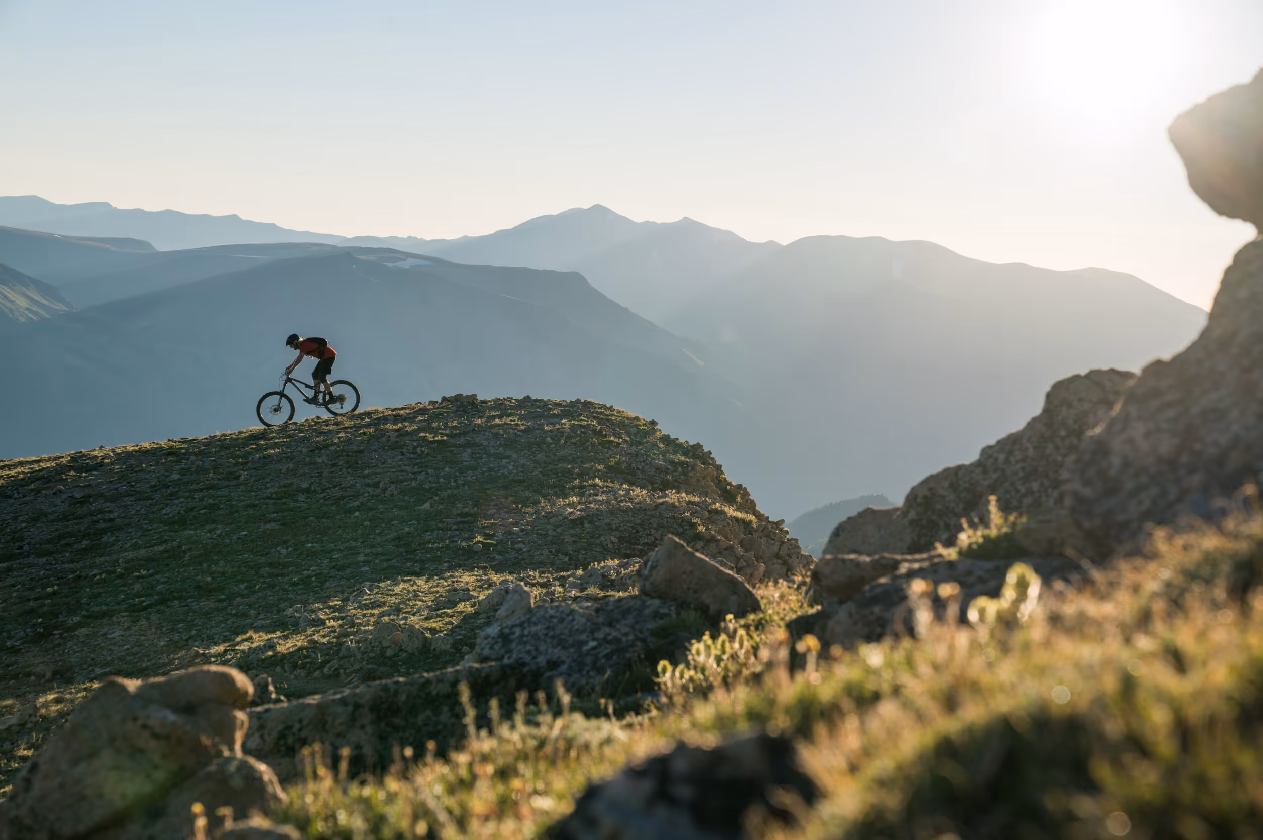 A silhouette of a mountain biker on a ridge just before sunset 