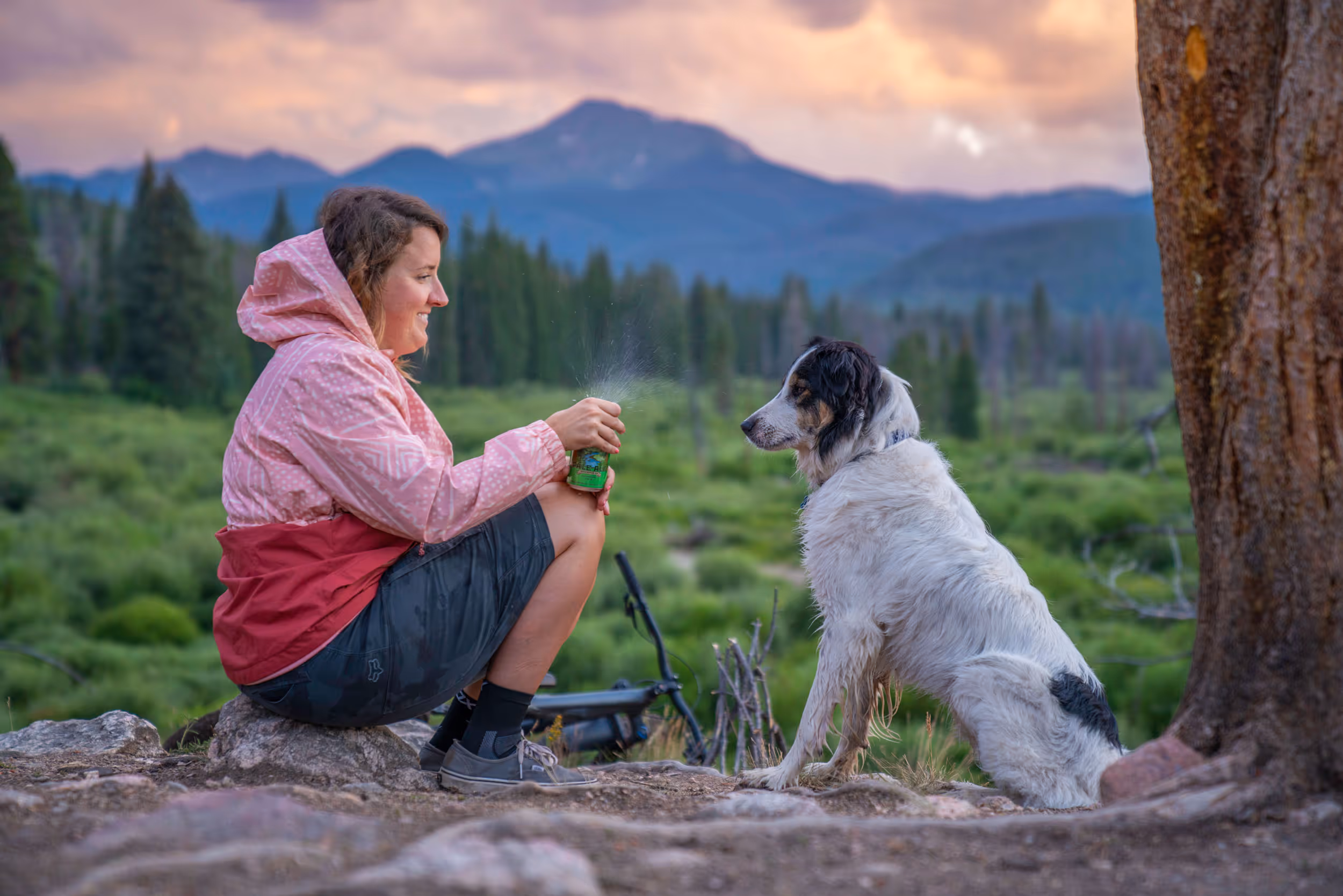 A woman and her pup enjoying the sunset from a bench overlooking the mountains