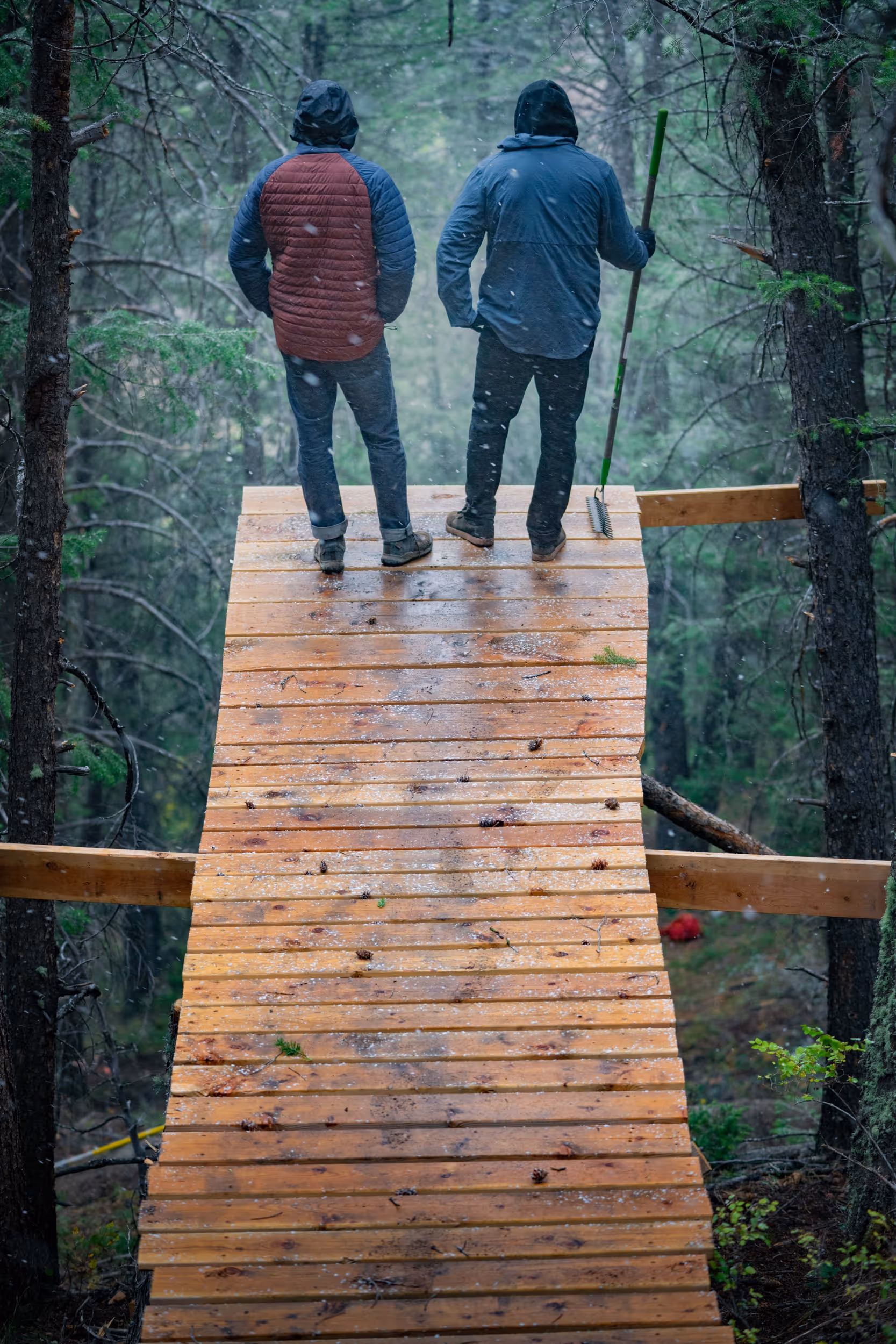 2 mountain bikers assessing the drop off of a bike jump 
