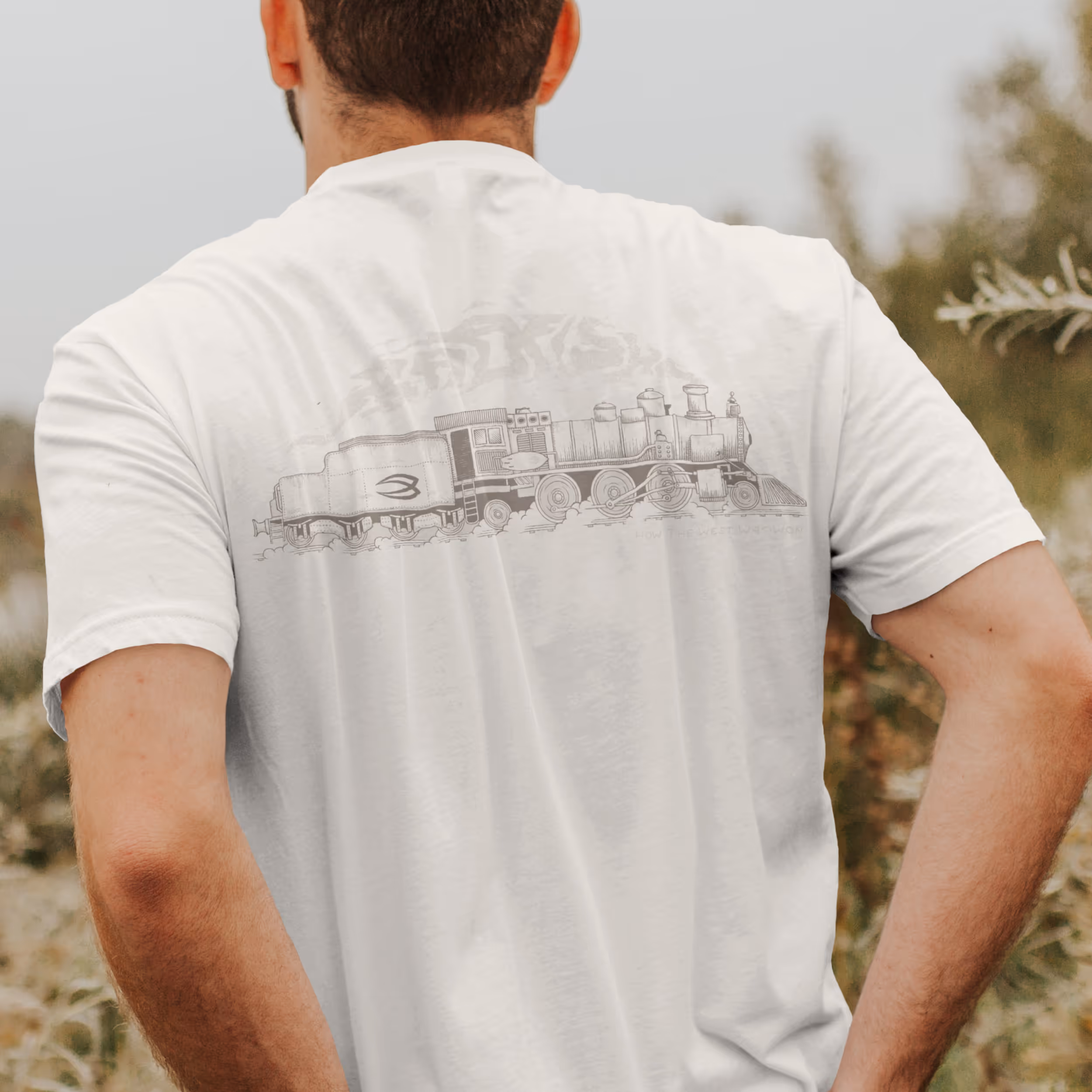 A man wearing a white tshirt with the old school locomotive graphic on the back of the shirt 