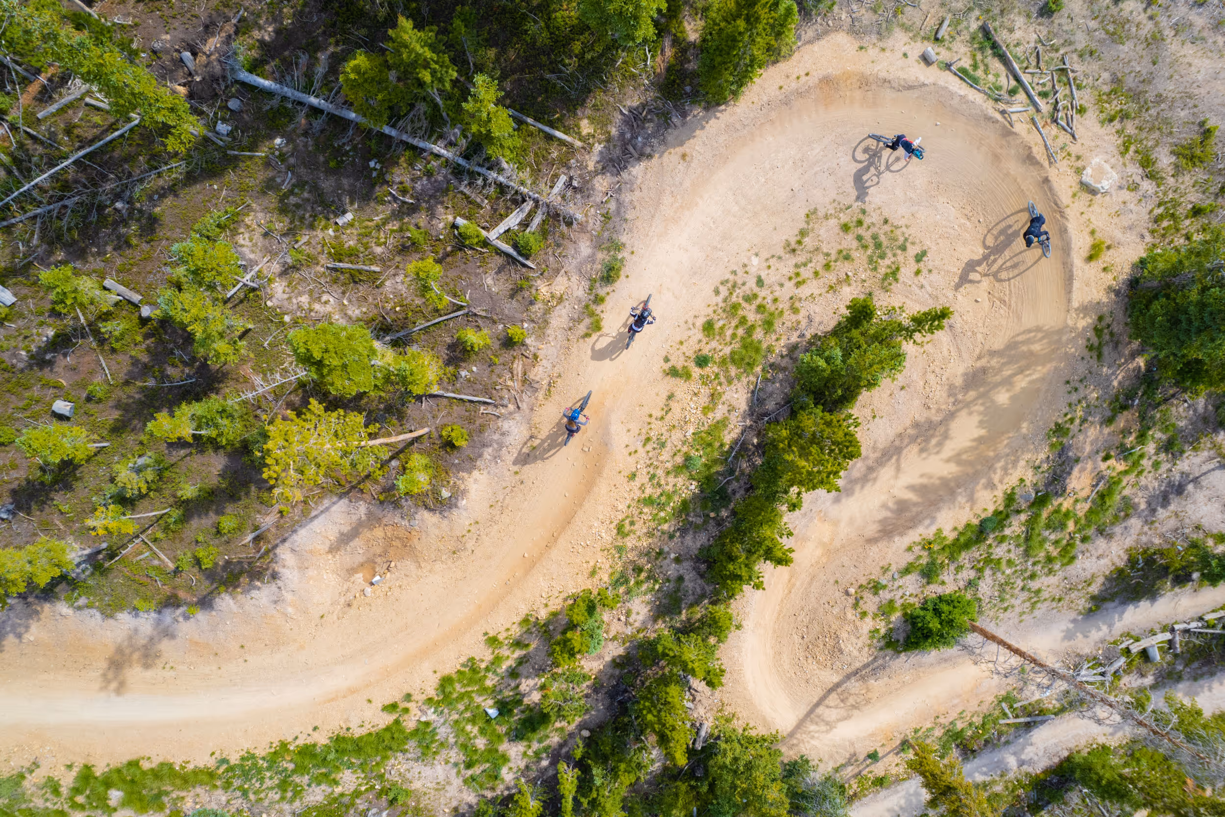 A crows eye view of 4 mountain bikers hitting a sharp berm 
