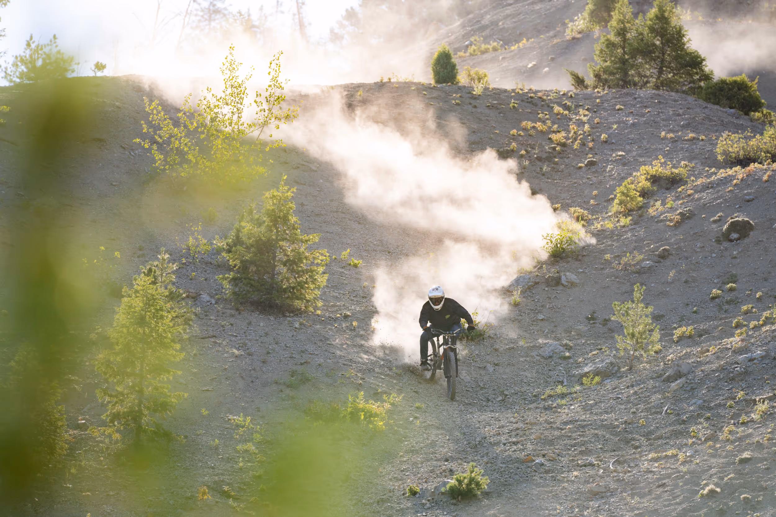 A mountain biker riding down a steep, dusty trail 