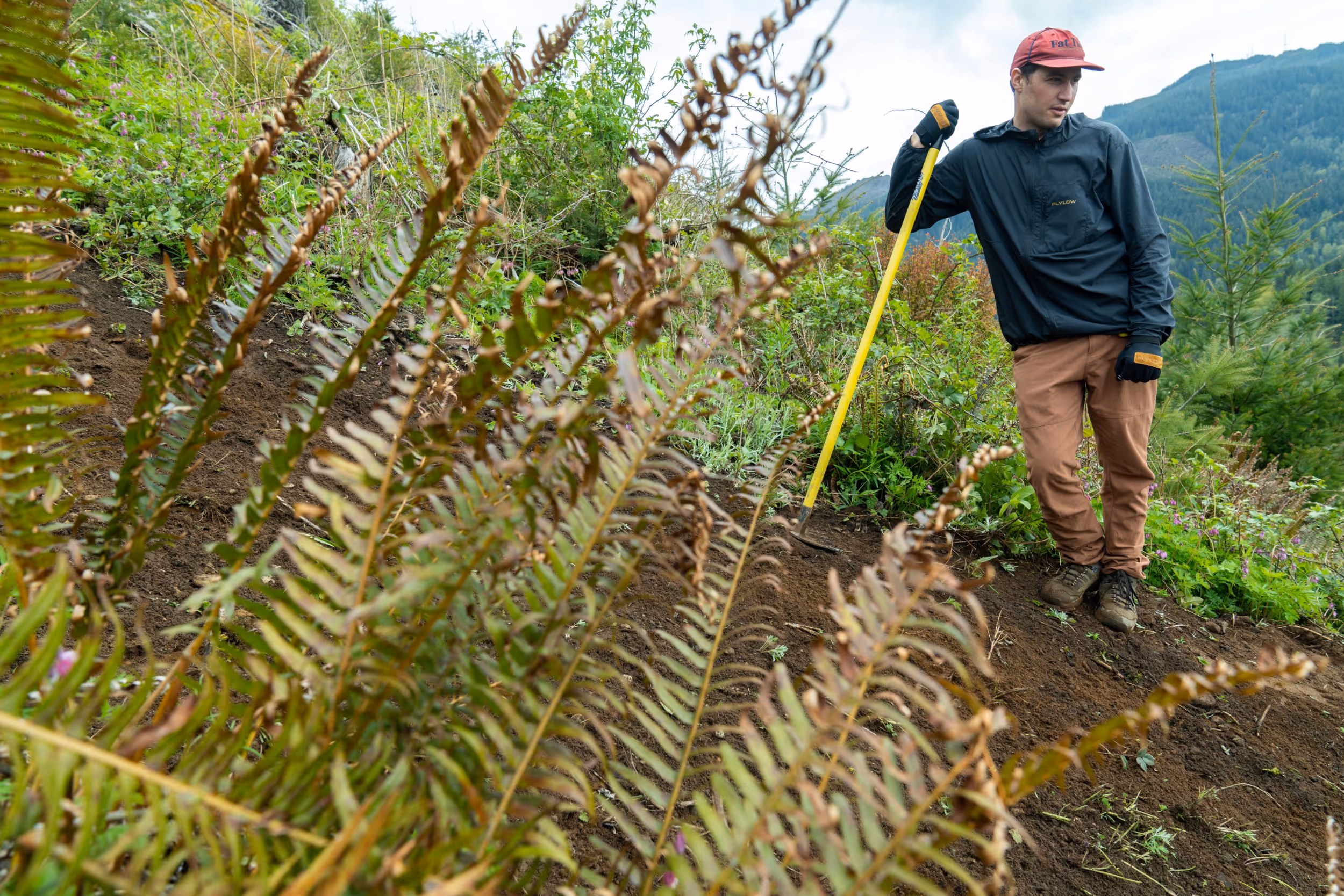 A man admiring his work after completing some mountain bike trail maintenance 