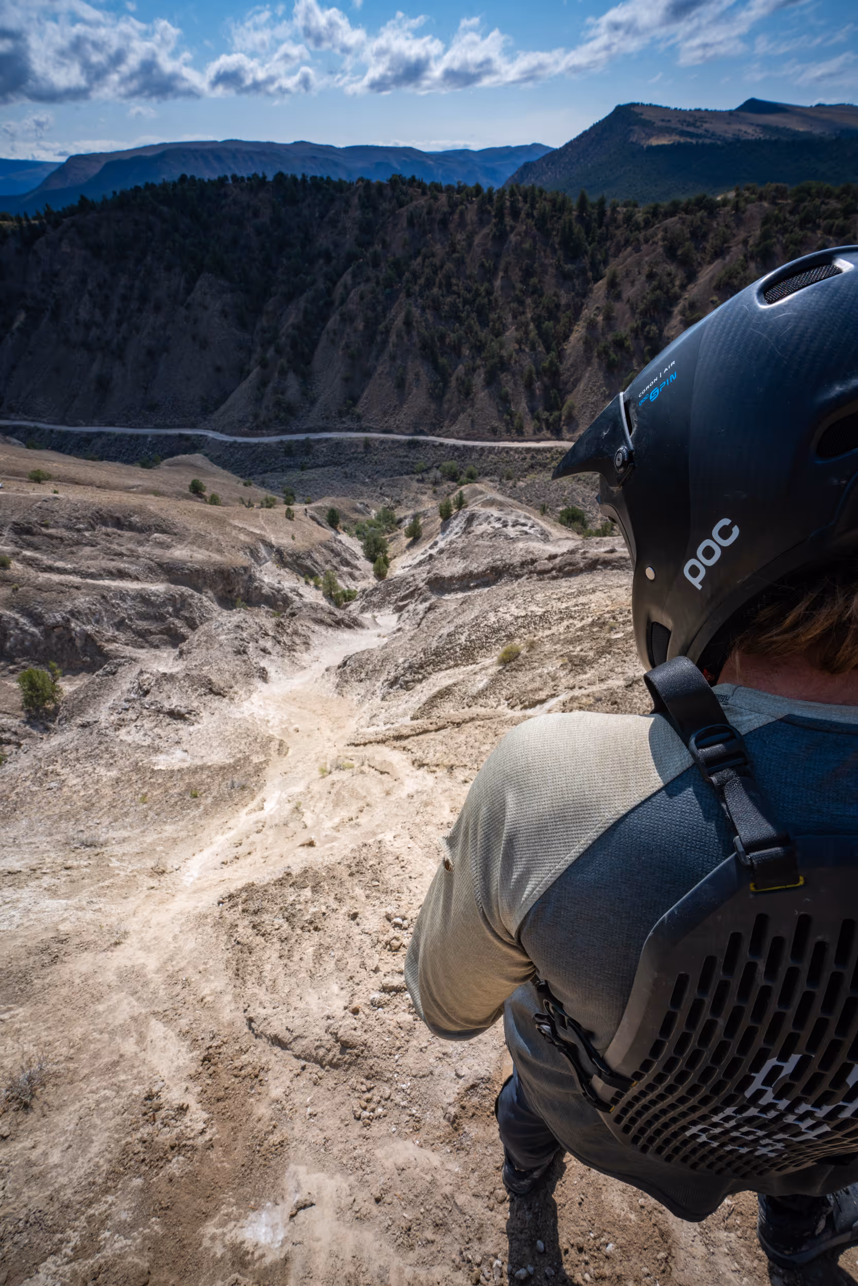 A mountain biker scouting a steep trail in front of him 