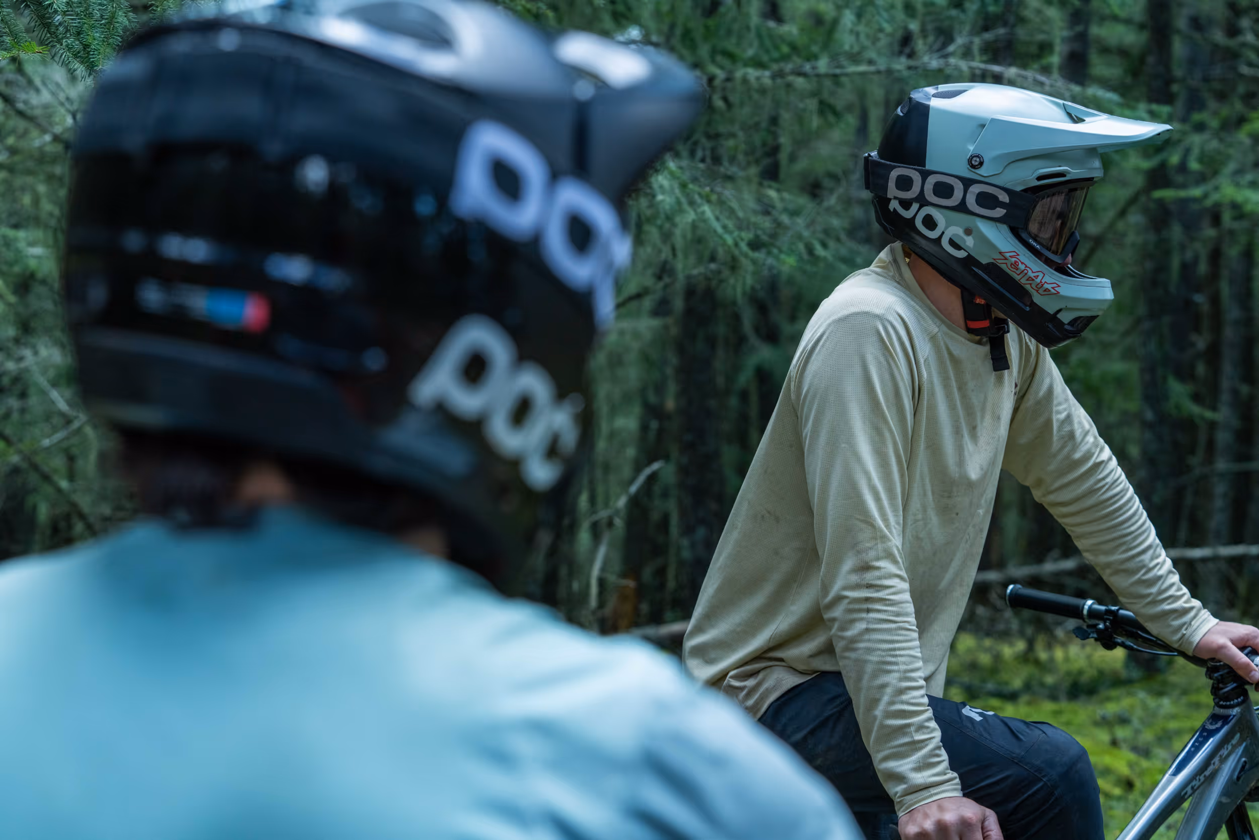 2 men wearing POC mountain biking helmets reconvening after a tricky section of trail 