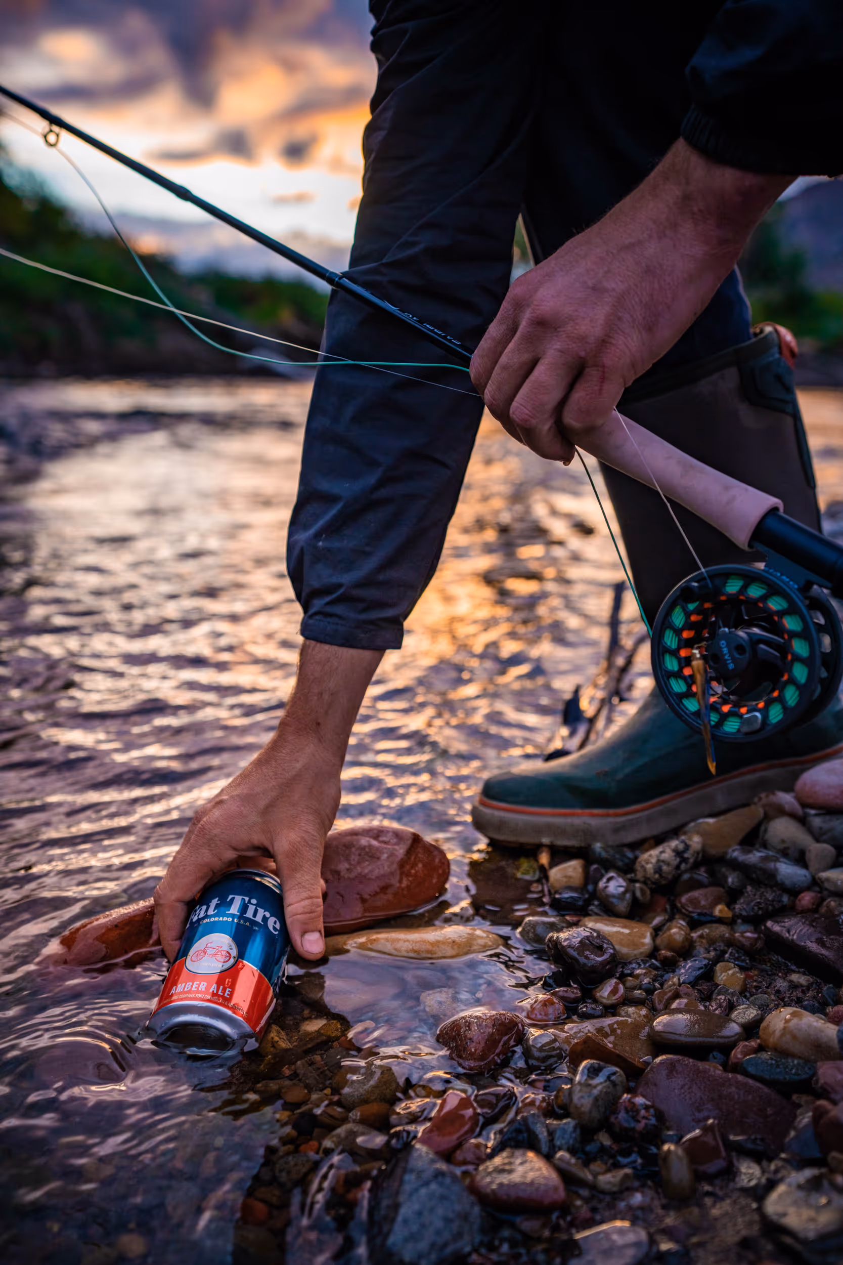 A fly fisherman setting his Fat Tire beer in the river so it can get cold 