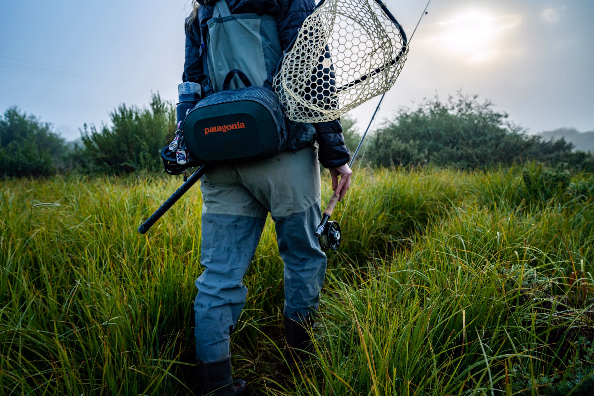 An up close shot of a fly fisher woman heading out to her favorite fishing spot through the fog 