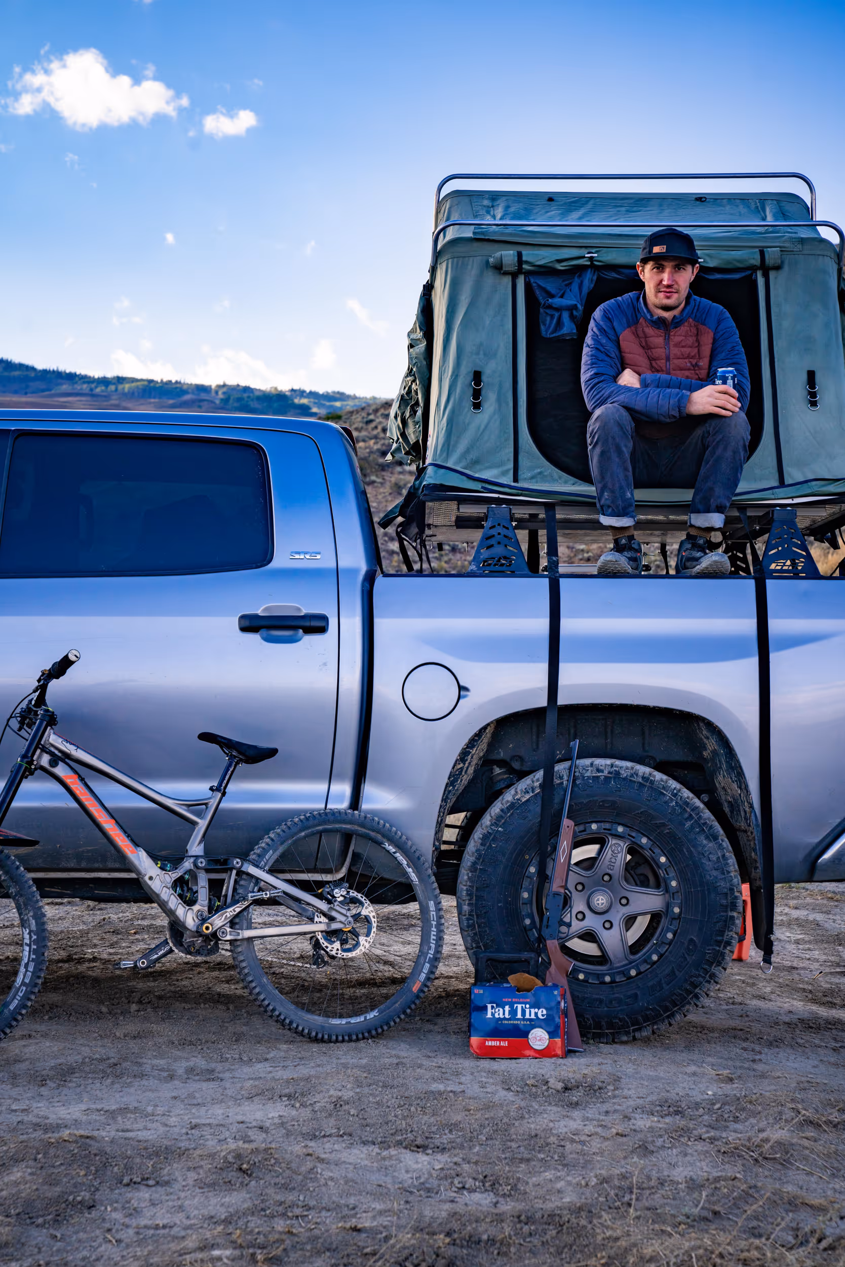 A man sitting in the the pop up truck tent after a day of riding 