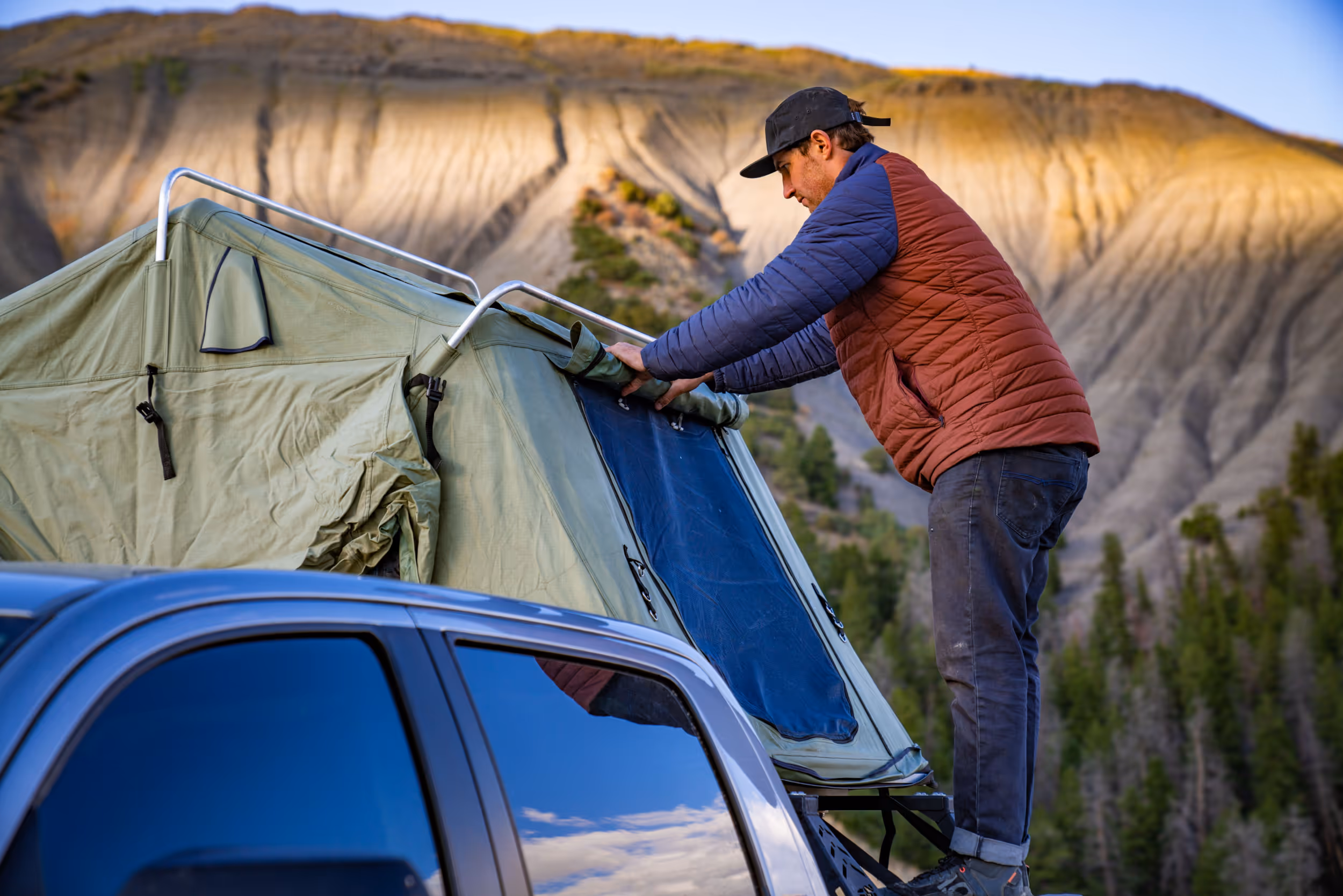 A man setting up his pop up tent on the back of his truck 