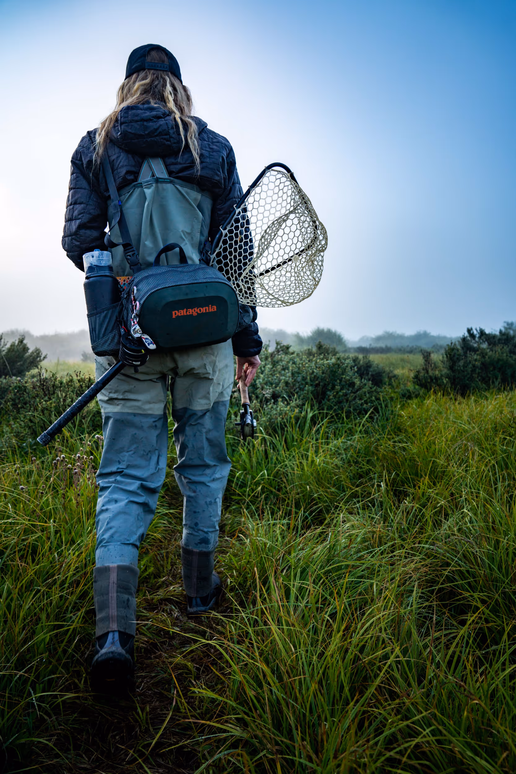 A fly fisher woman heading out to her favorite fishing spot through the fog 