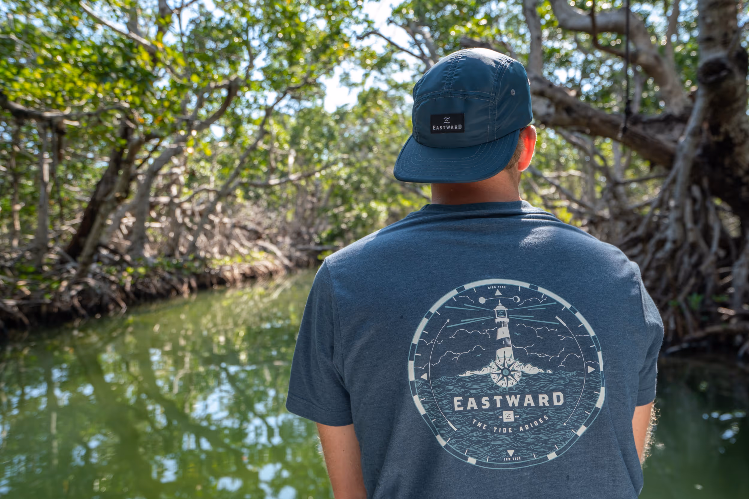 Man wearing Eastward t-shirt while looking over the side of a sail boat