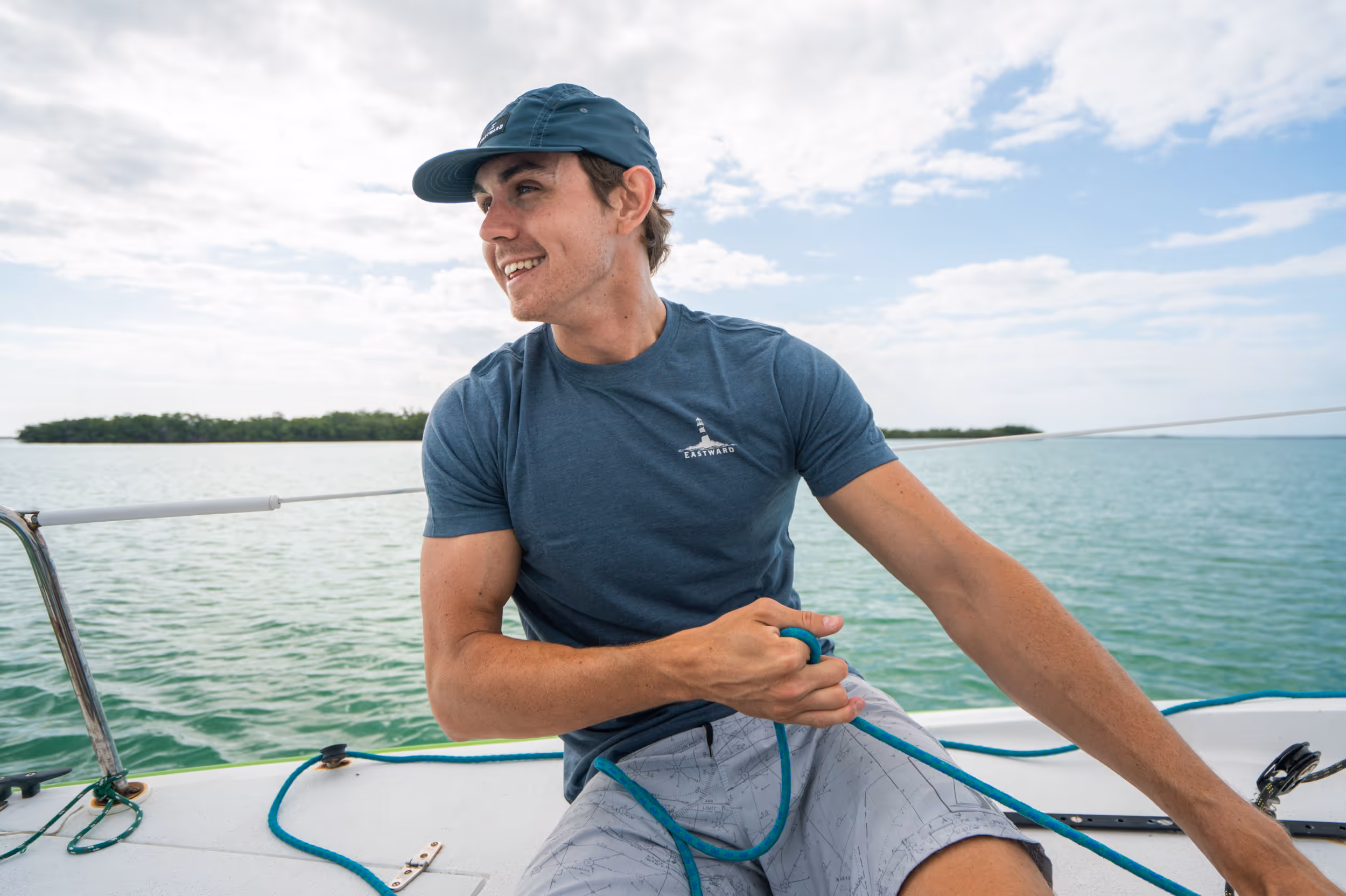 A man wearing an Eastward t-shirt while working on a sail boat 