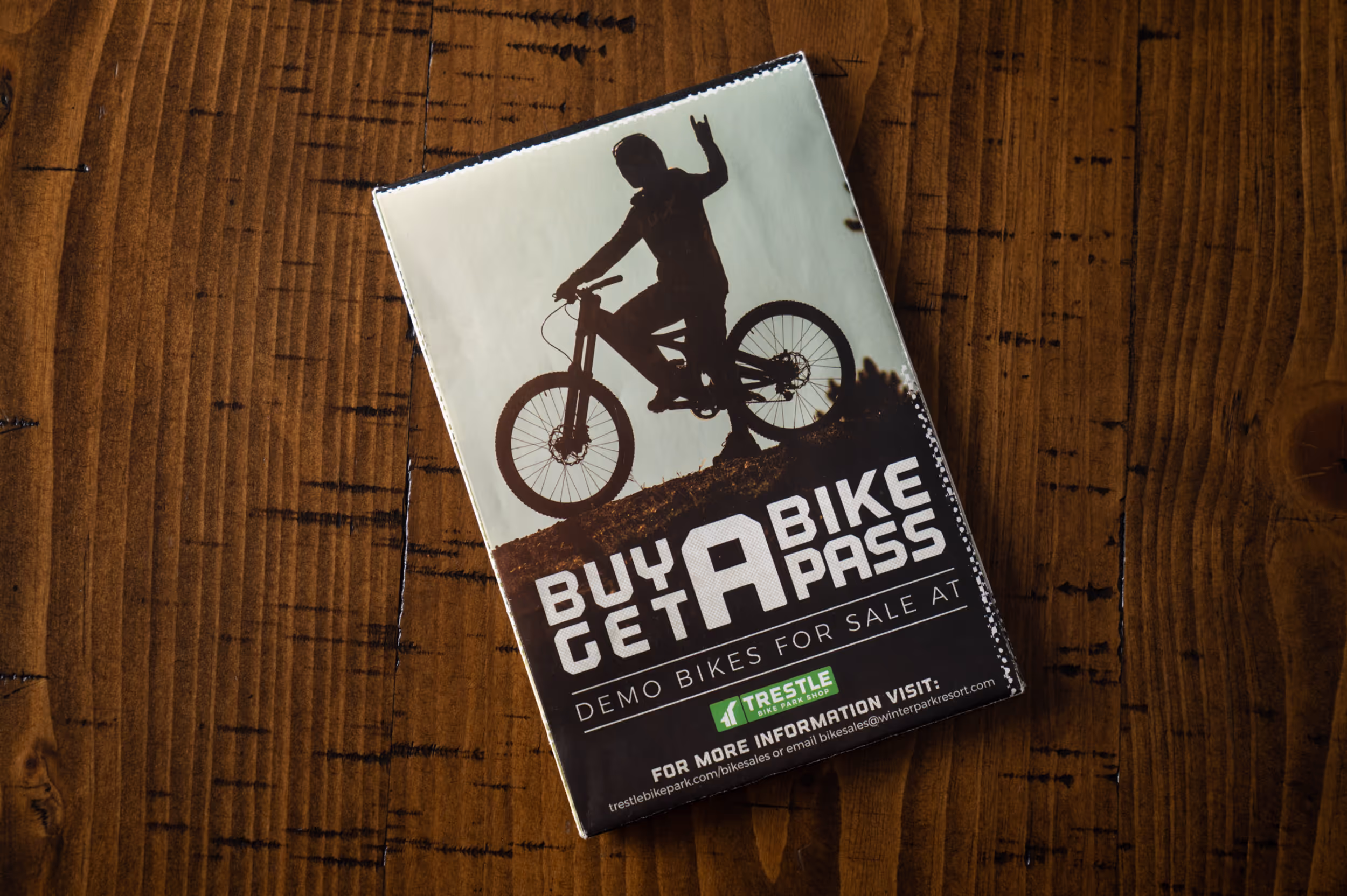 A bike park pass voucher showing the outline of a mountain biker holding their hands in a "rock on" gesture 
