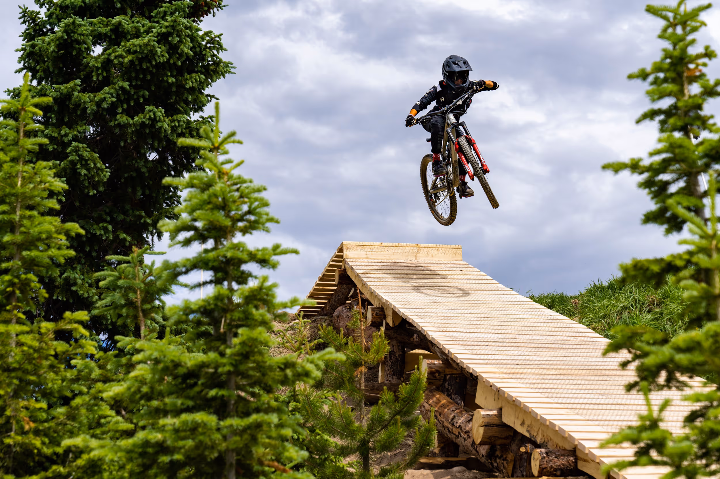 A mountain biker mid air on a wooden jump 
